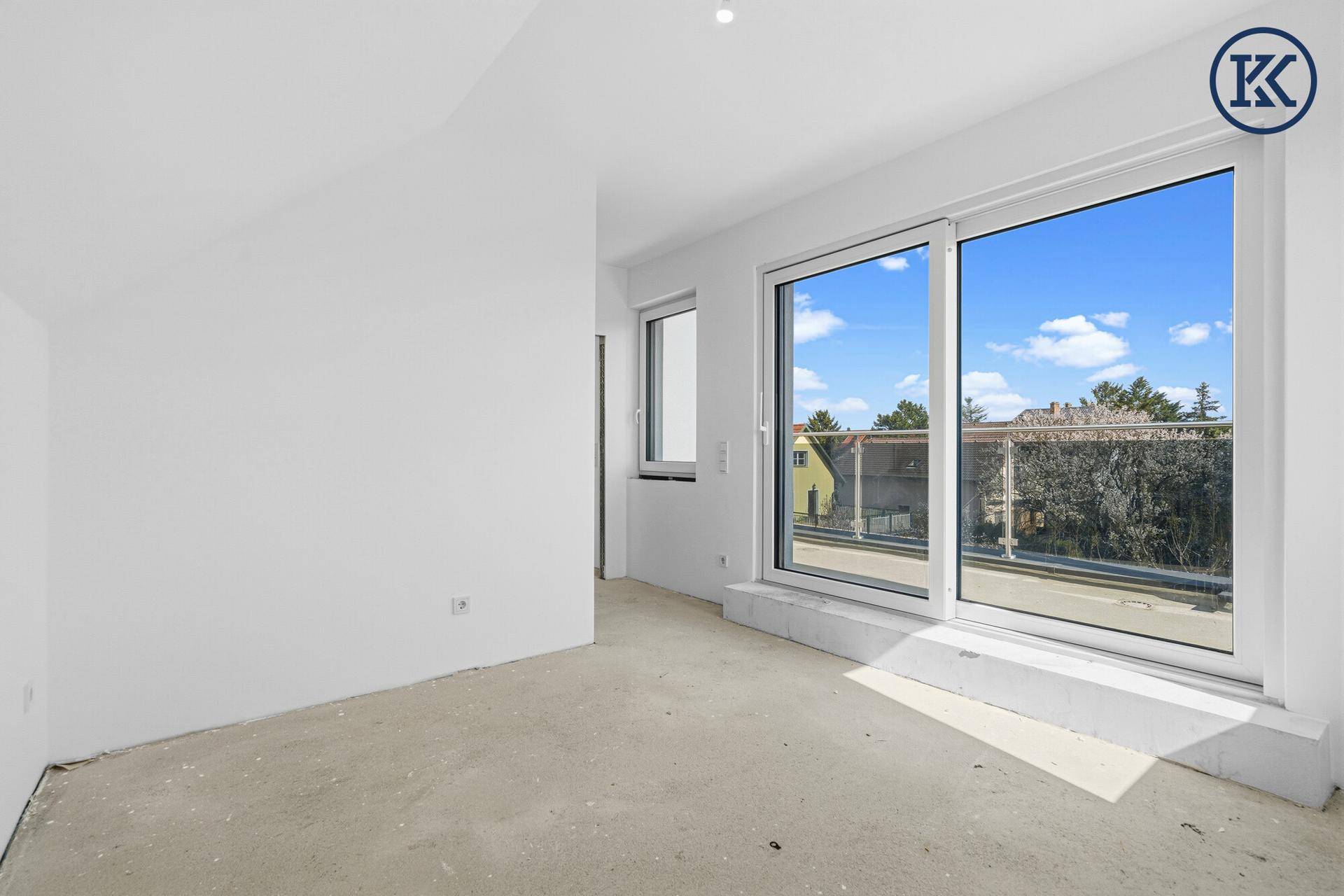 Heller Raum im Rohbau mit großem Schiebefenster und Zugang zu einem Balkon.