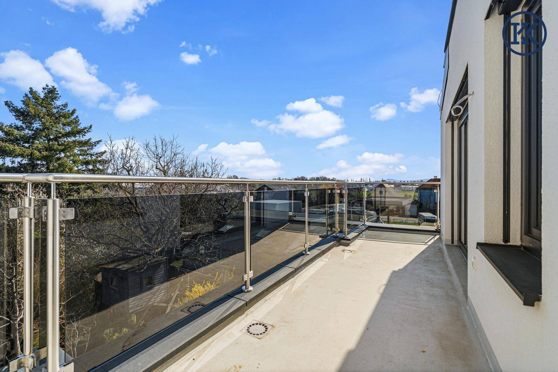 Geräumiger Balkon mit Glasgeländer und weitem Blick über die Nachbarschaft.