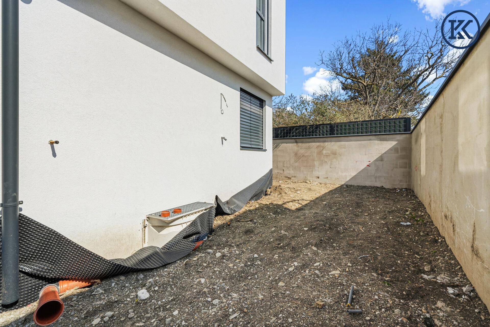 Gartenbereich im Rohbau mit Erdboden und vorbereiteten Flächen für die Gestaltung.
