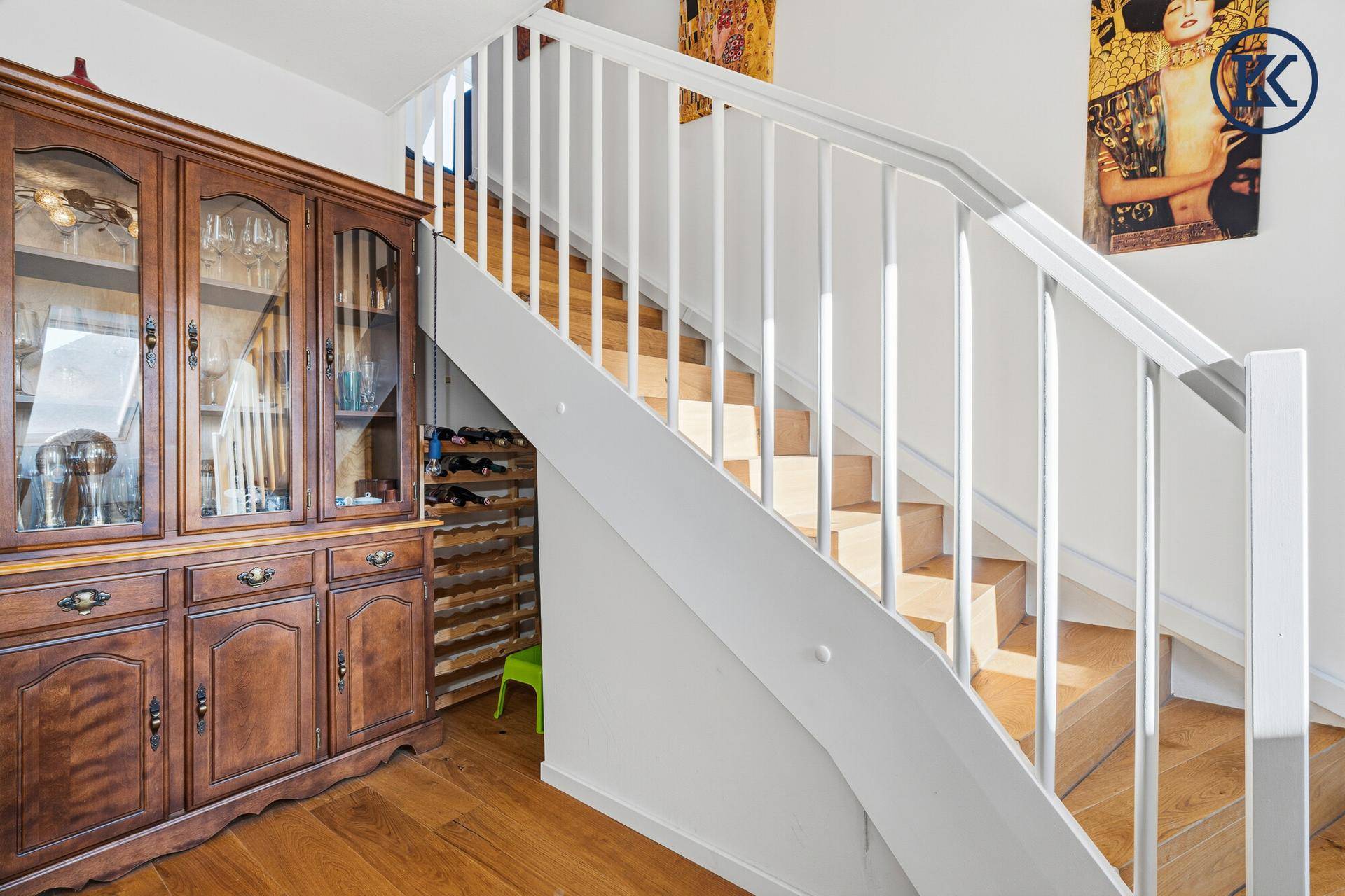 Heller Treppenaufgang mit Holzstufen und einem antiken Holzschrank.