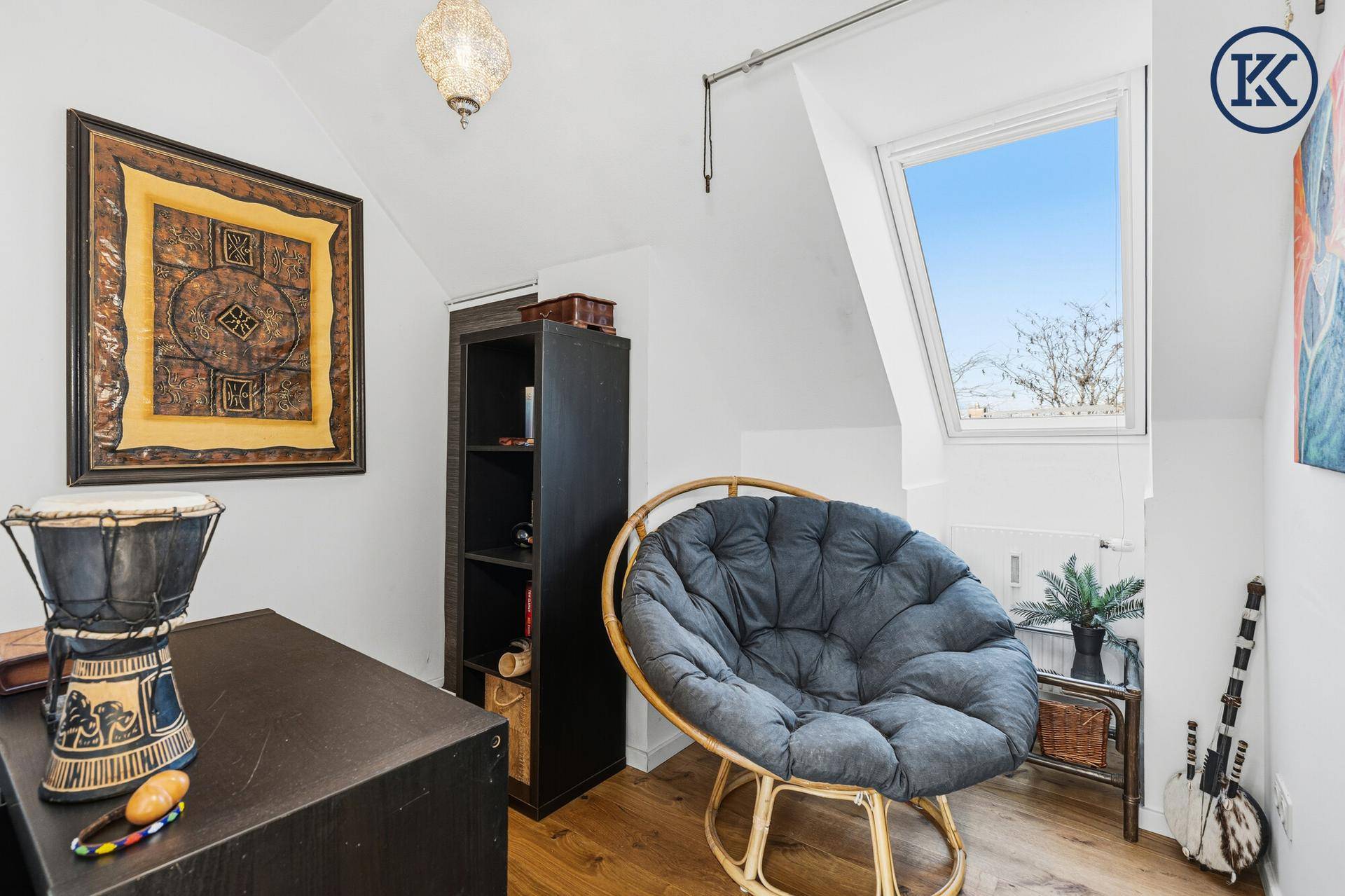 Gemütliche Leseecke im Dachgeschoss mit Rattan-Sessel und Dachfenster.