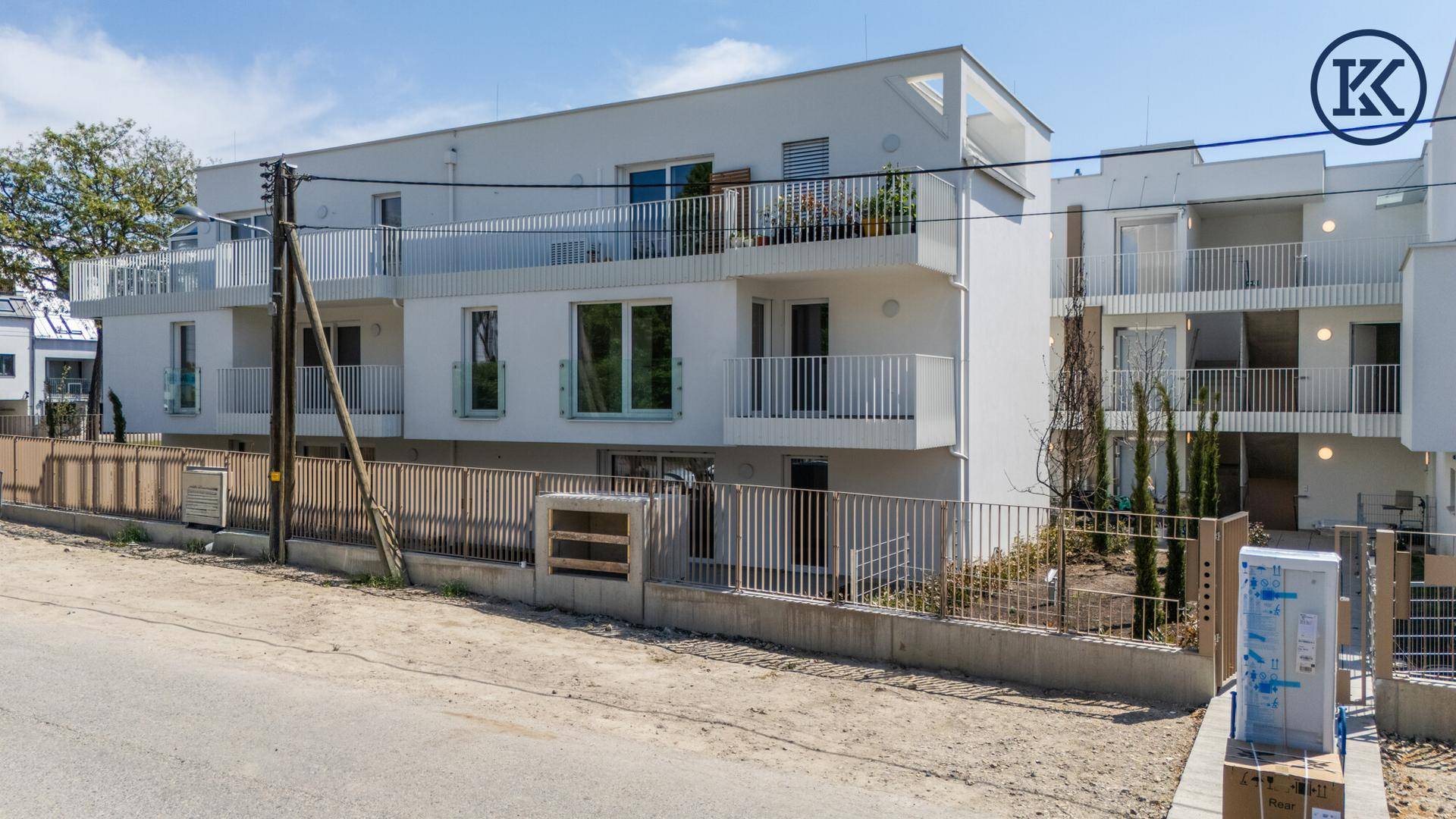 Ansicht der modernen Wohnanlage von der Straße mit weißen Balkonen und großen Fenstern.