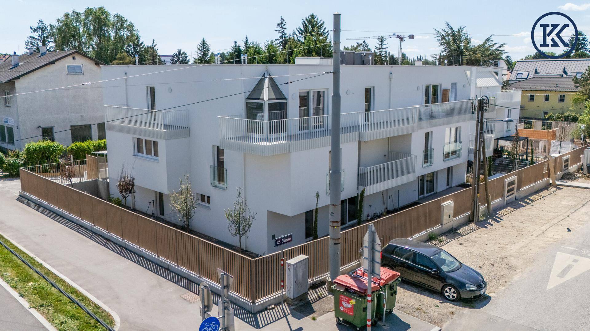 Eckansicht des modernen Gebäudes von oben mit markantem Balkon und der umliegenden Straße.