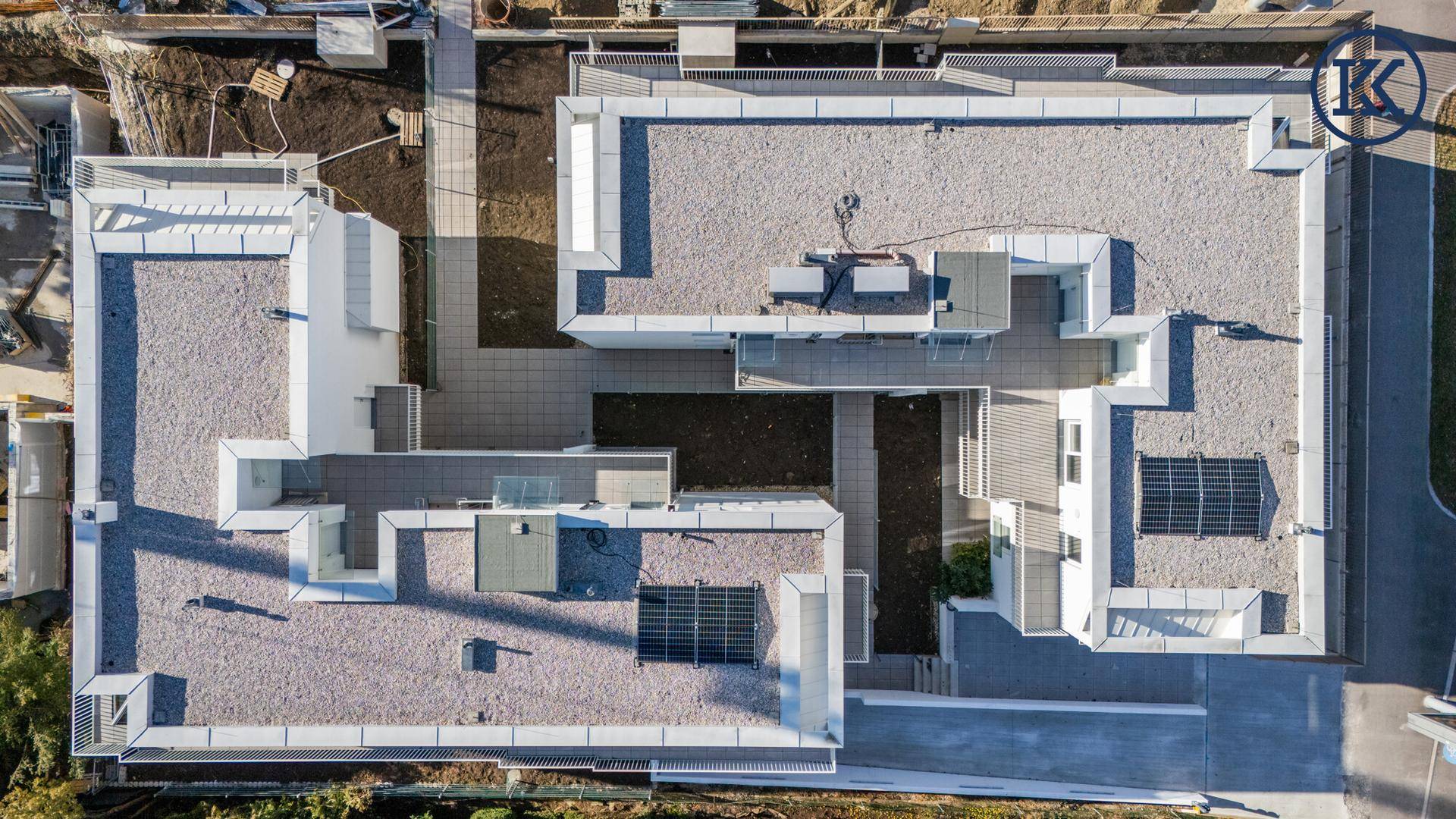 Draufsicht auf die moderne Wohnanlage mit Flachdächern, Innenhöfen und Solarpaneelen.