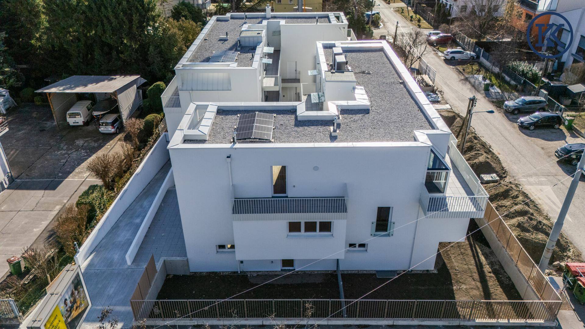 Luftaufnahme eines modernen Apartmentgebäudes mit Flachdach und installierten Solarmodulen.