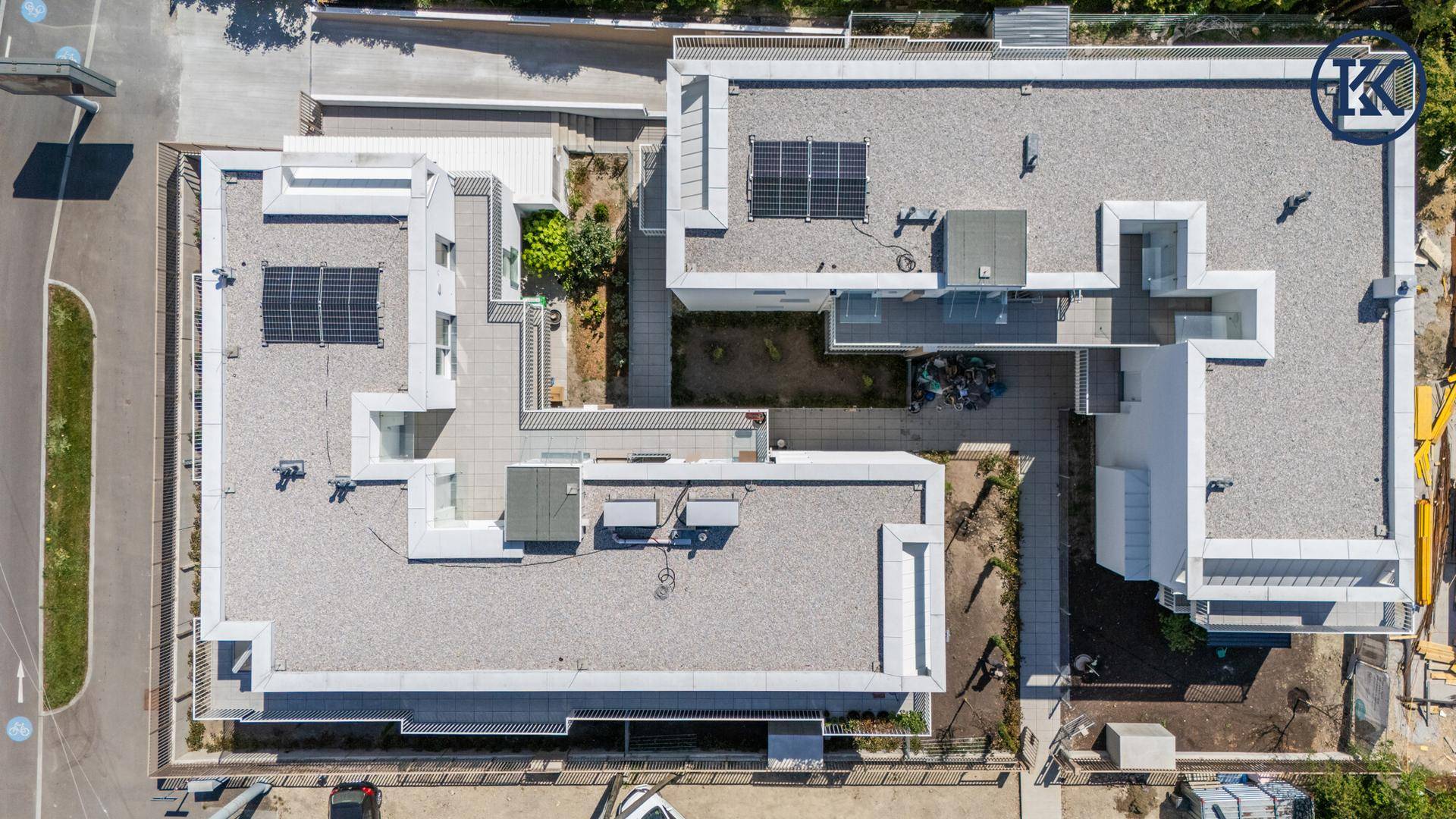 Vogelperspektive eines modernen Wohnkomplexes mit Flachdächern und Solarpaneelen.