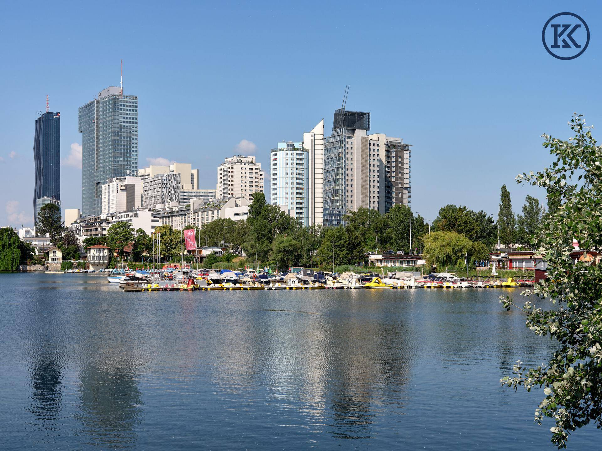 Weitblick über den See mit zahlreichen Booten und der beeindruckenden Skyline der Stadt im Hintergrund.