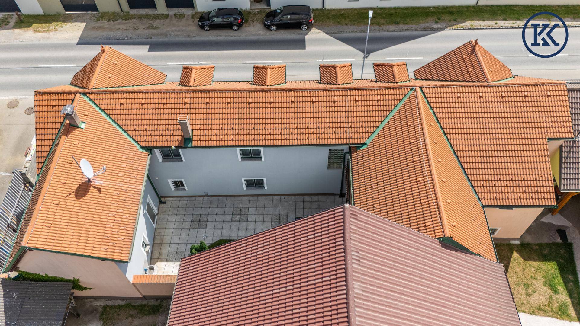 Dachansicht des Gebäudes mit mehreren Ziegeldächern und Innenhof.