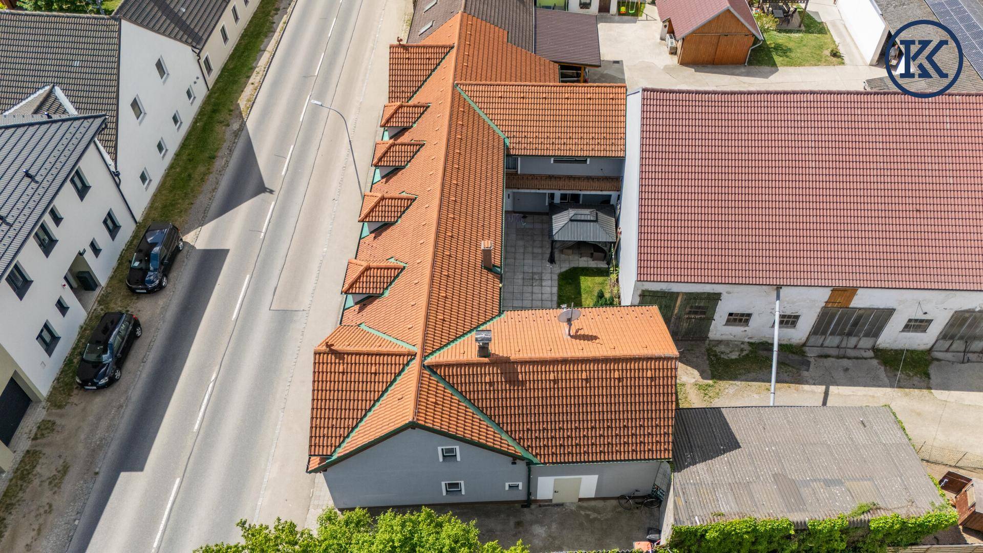 Luftaufnahme des Anwesens mit langem Gebäude, Ziegeldach und angrenzender Straße.