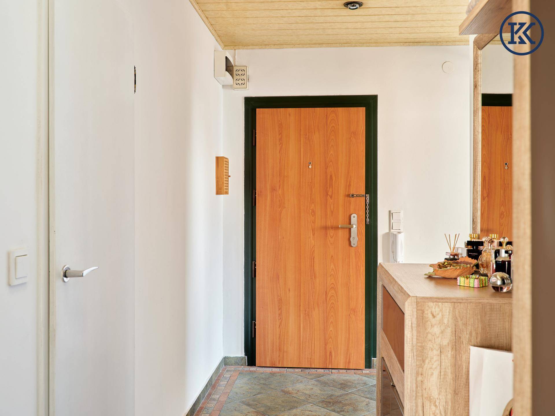 Eingangsbereich der Wohnung mit Holztür, Holzdecke und gefliestem Boden.
