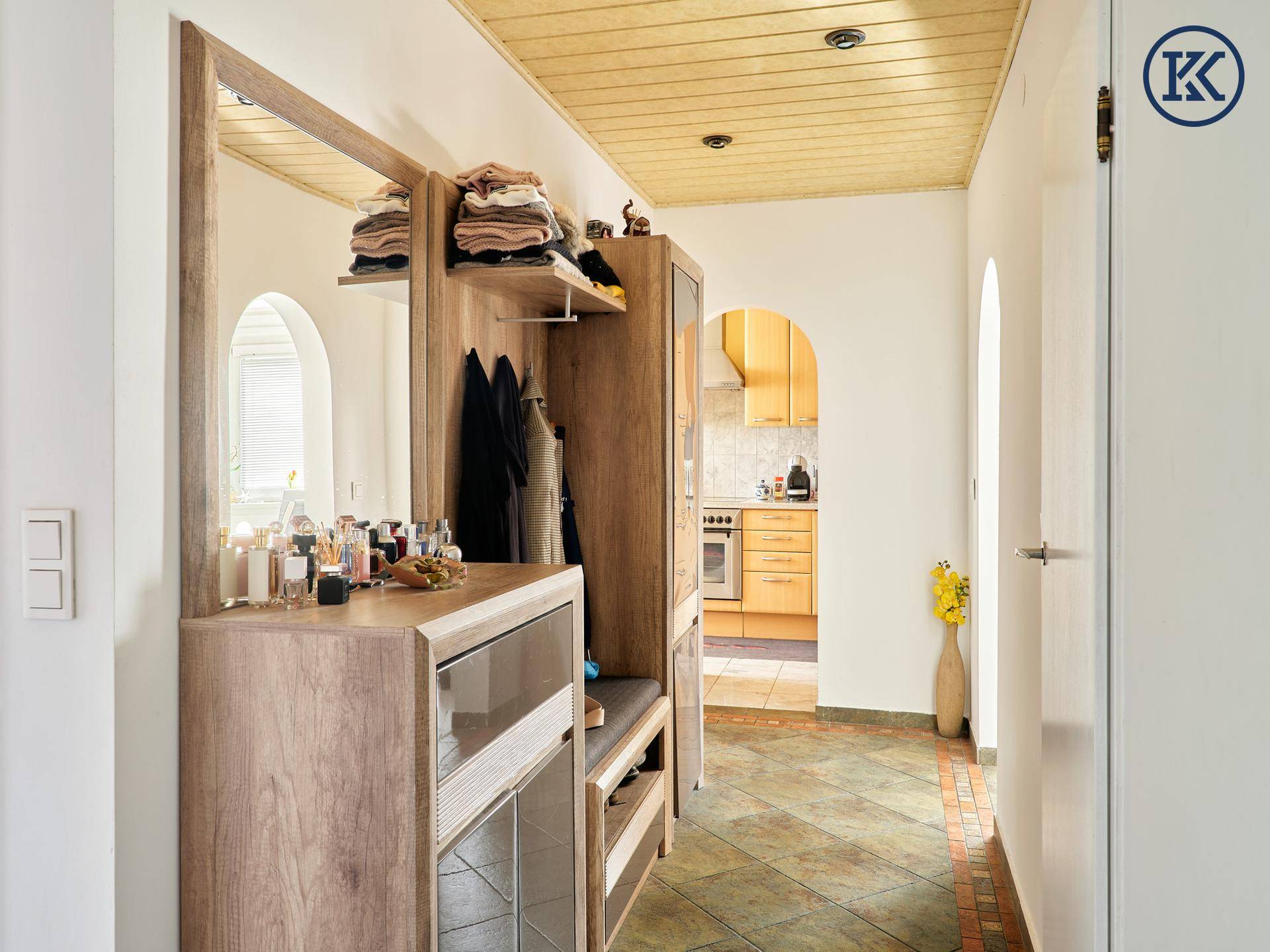 Geräumiger Flur mit Garderobe, Spiegel und Durchgang zu einer Küche im Hintergrund.