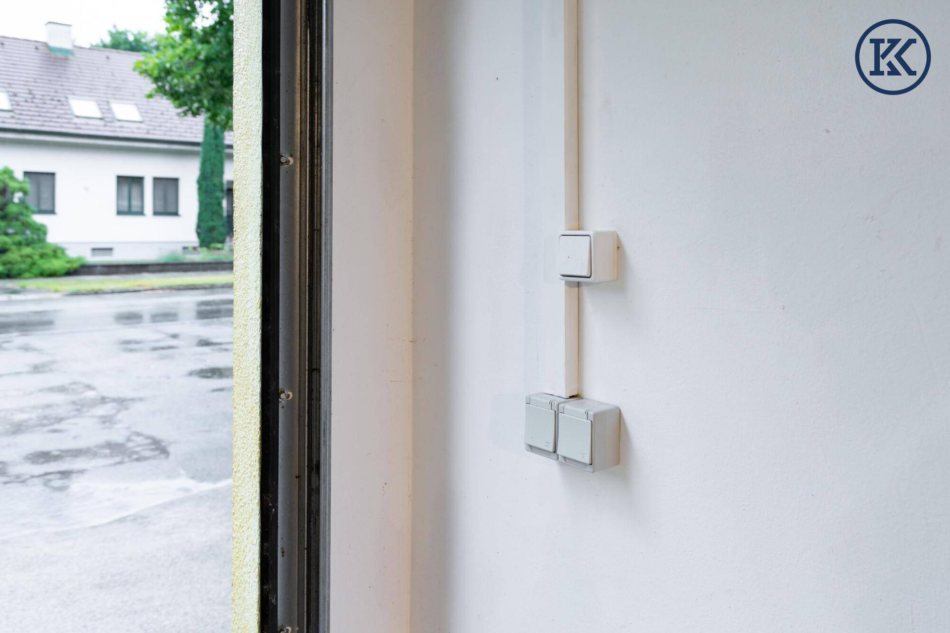 Elektrische Steckdosen und Verkabelung an einer weißen Wand neben einem Fensterrahmen.