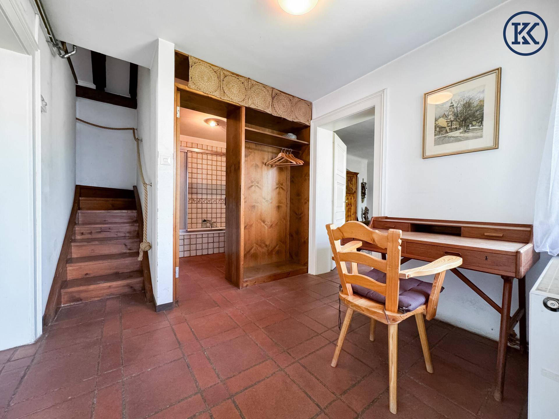 Flur mit Terrakotta-Fliesenboden, Holzschreibtisch und eingebautem Holzschrank.