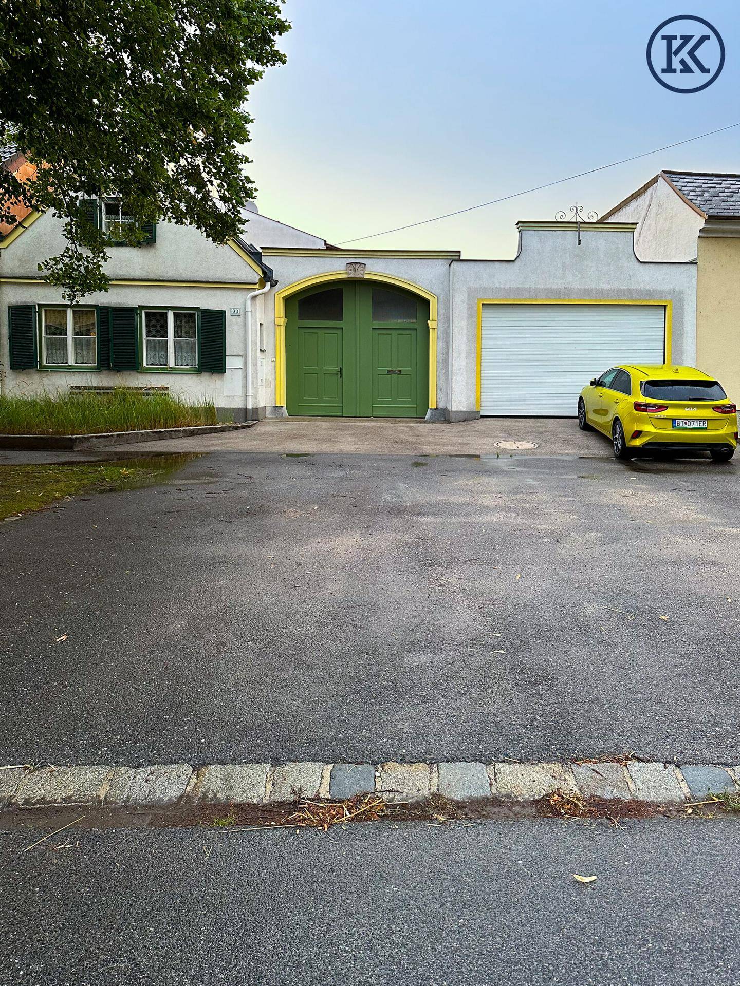 Fassade des Gebäudes mit zwei Garagentoren und einem geparkten gelben Auto.