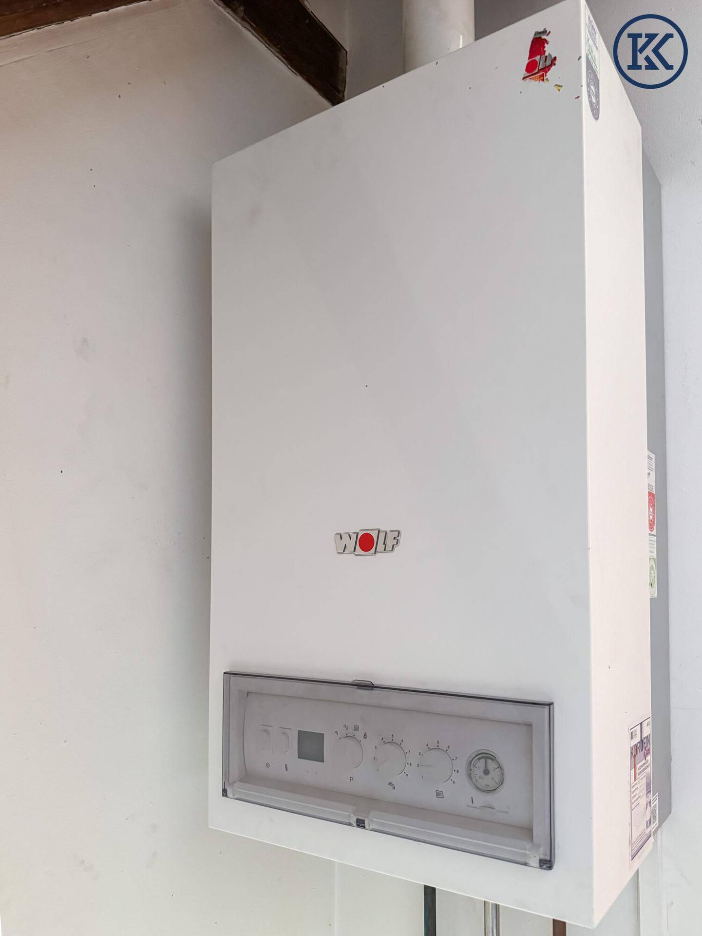 Wandmontierter weißer Heizkessel der Marke Wolf in einem funktionalen Technikraum.