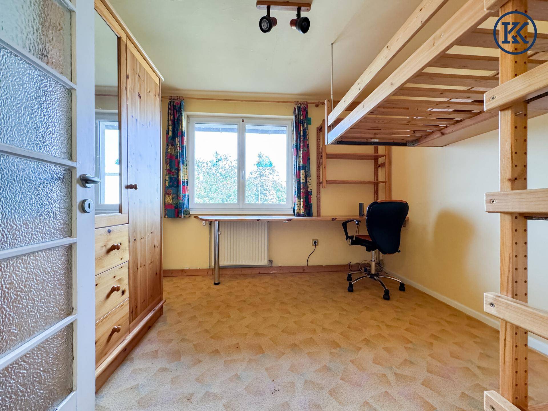 Helles Schlafzimmer mit Hochbett, Schreibtisch, Holzschrank und Blick ins Grüne.