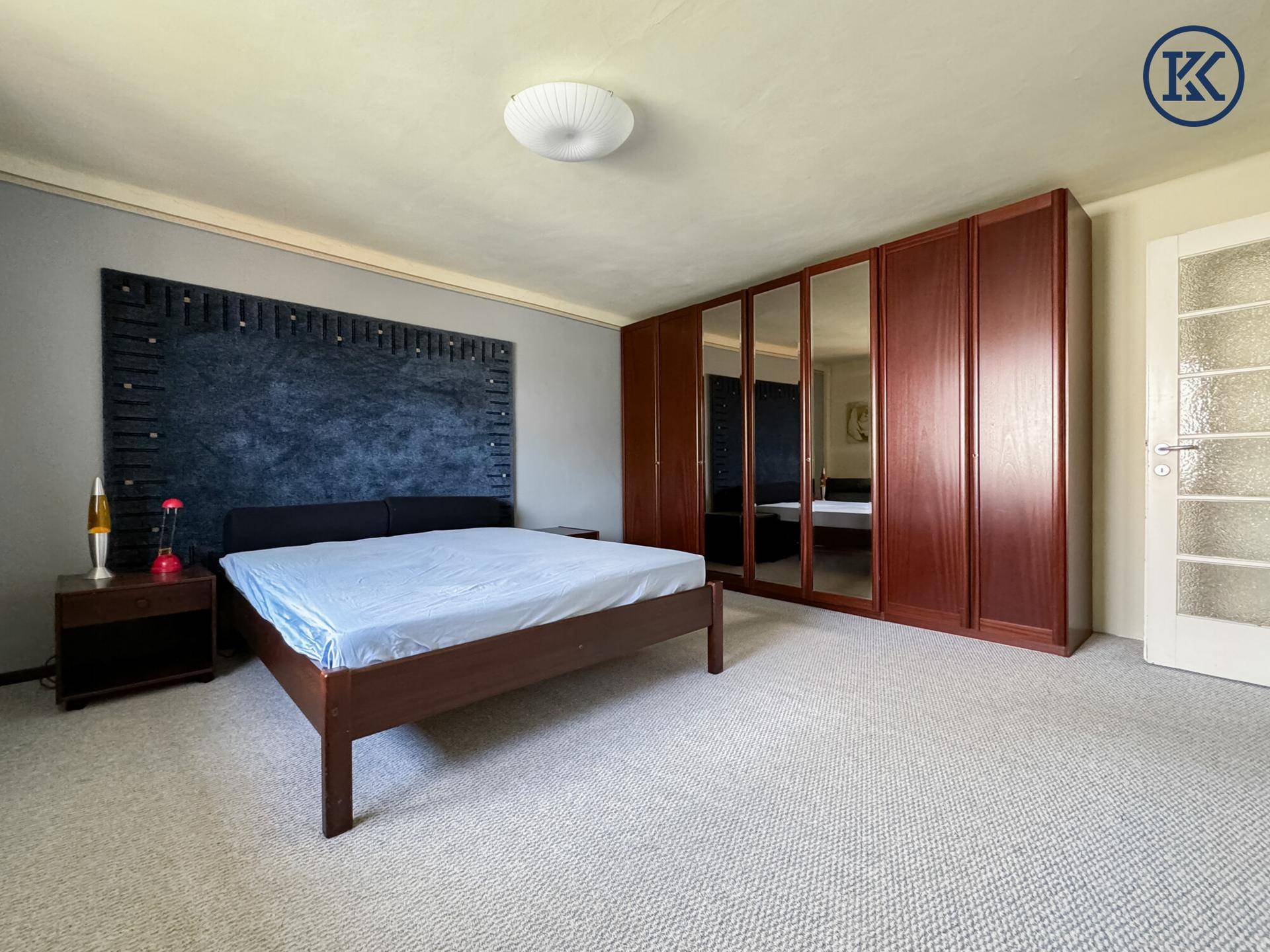 Schlafzimmer mit großem Doppelbett, Spiegelschränken und einer Tür mit Milchglas-Einsätzen.