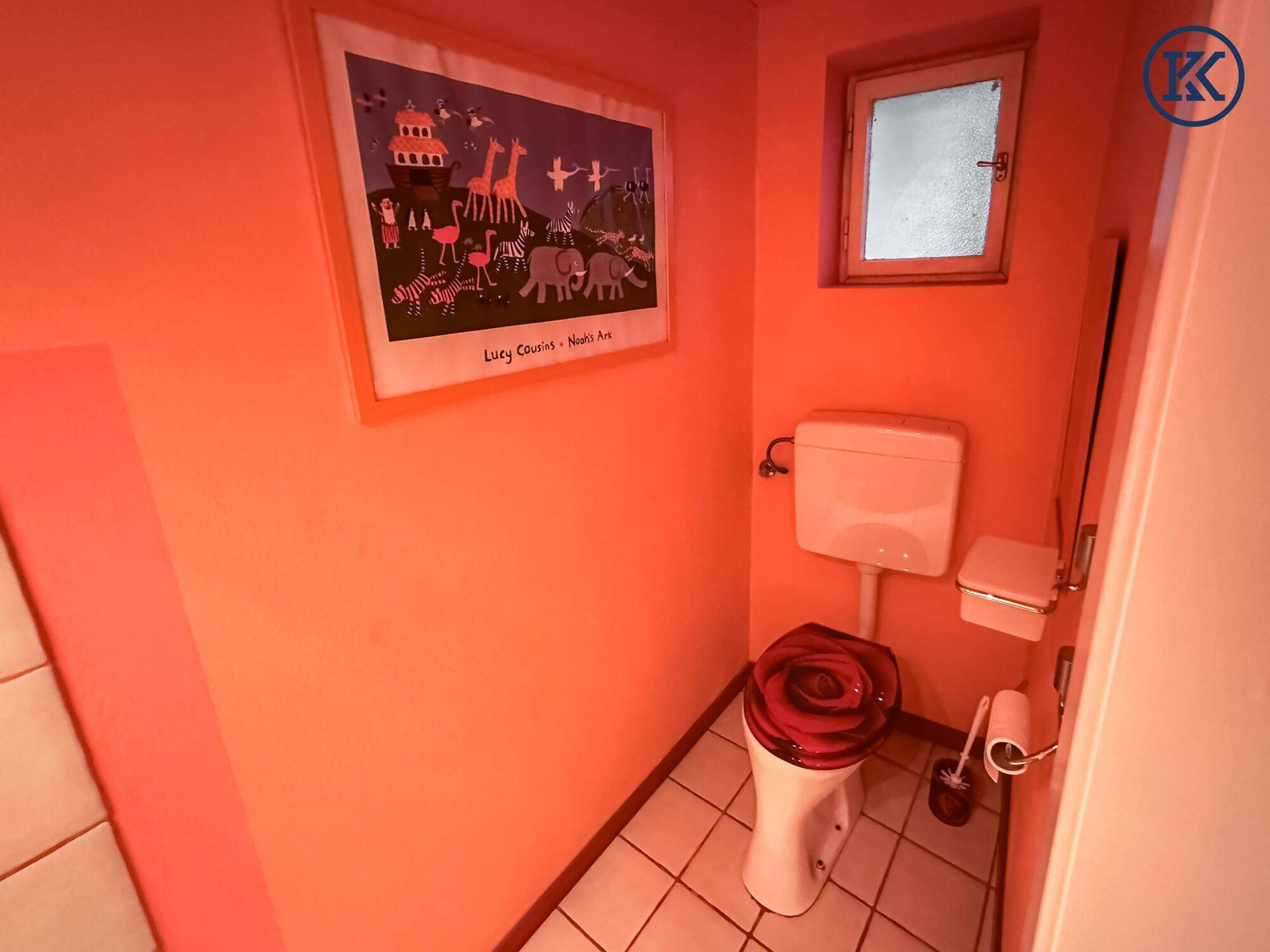 Farbenfrohes WC mit rosa Wänden, Fliesenboden und einem kleinen Fenster für Tageslicht.