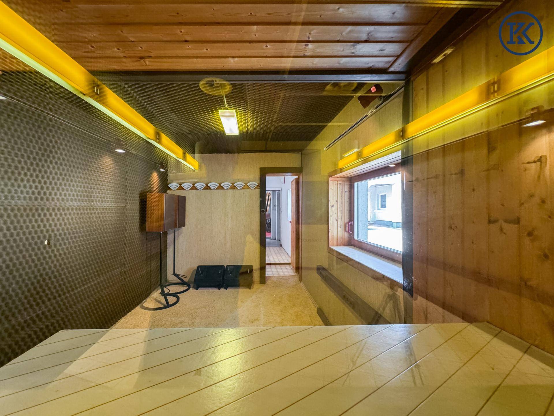 Innenraum mit Holzverkleidung an Wänden und Decke, Teppichboden und spezieller Akustik.