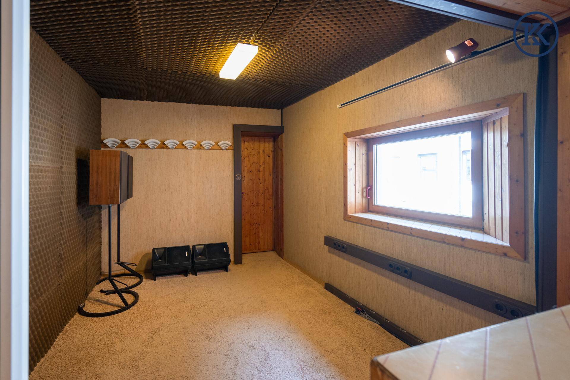 Innenraum mit Holzverkleidung, schallabsorbierenden Wänden und einem Fenster, das Tageslicht hereinlässt.