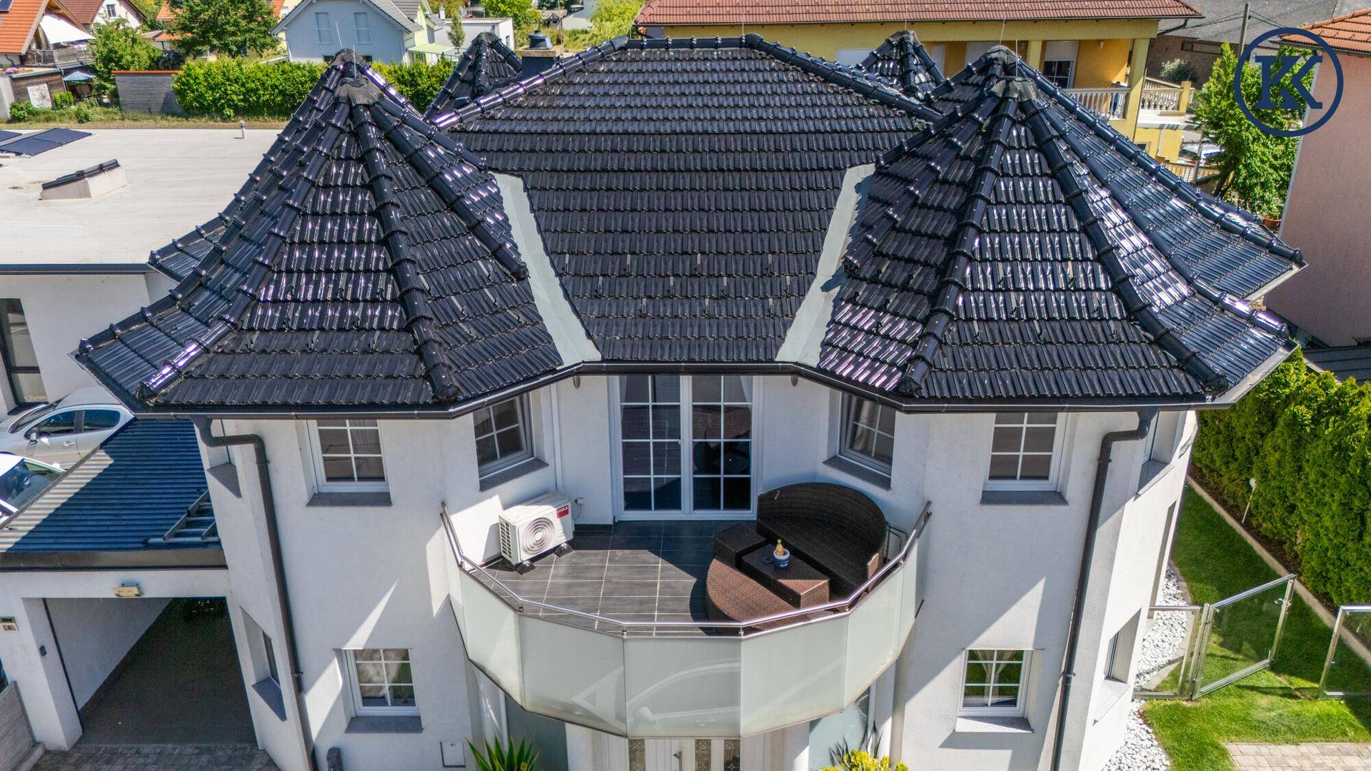 Elegante Fassade mit großem Balkon, modernen Fenstern und markantem Dach.