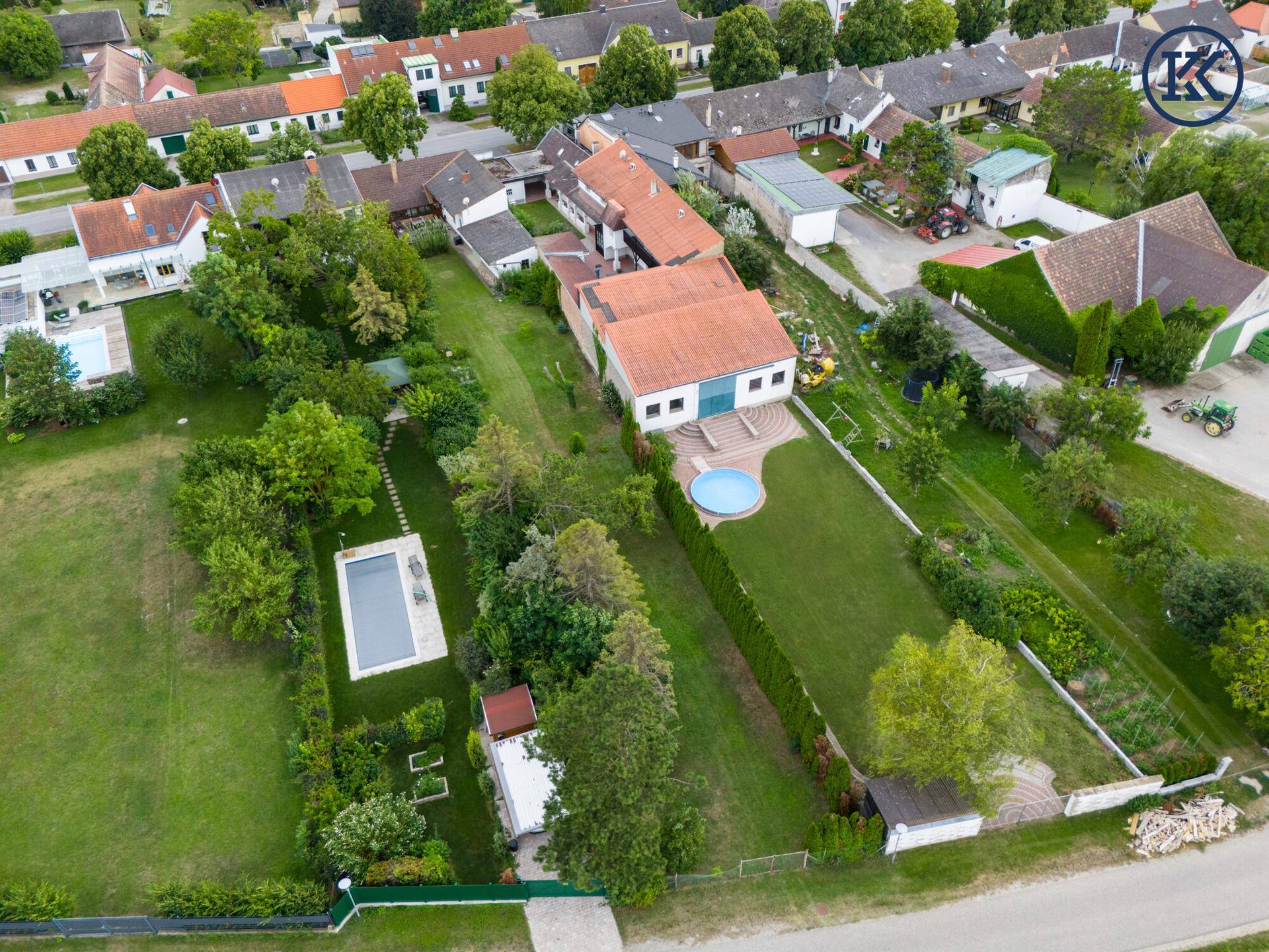 Luftaufnahme des weitläufigen Gartens mit Swimmingpool und angrenzendem Wohnhaus.