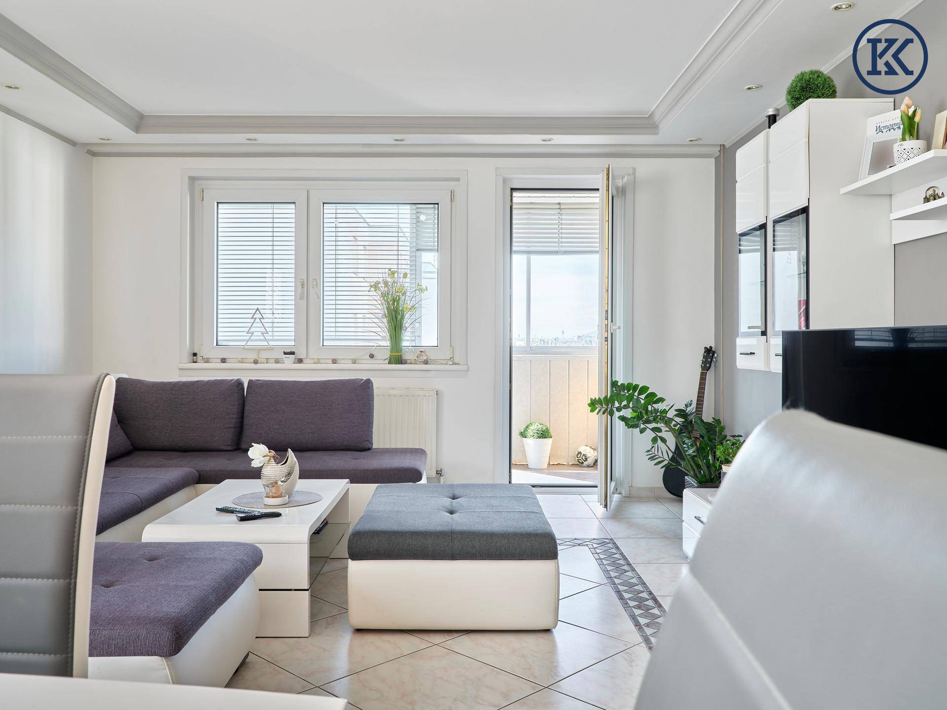 Heller Wohnbereich mit gemütlicher Sitzecke und Zugang zum Balkon.