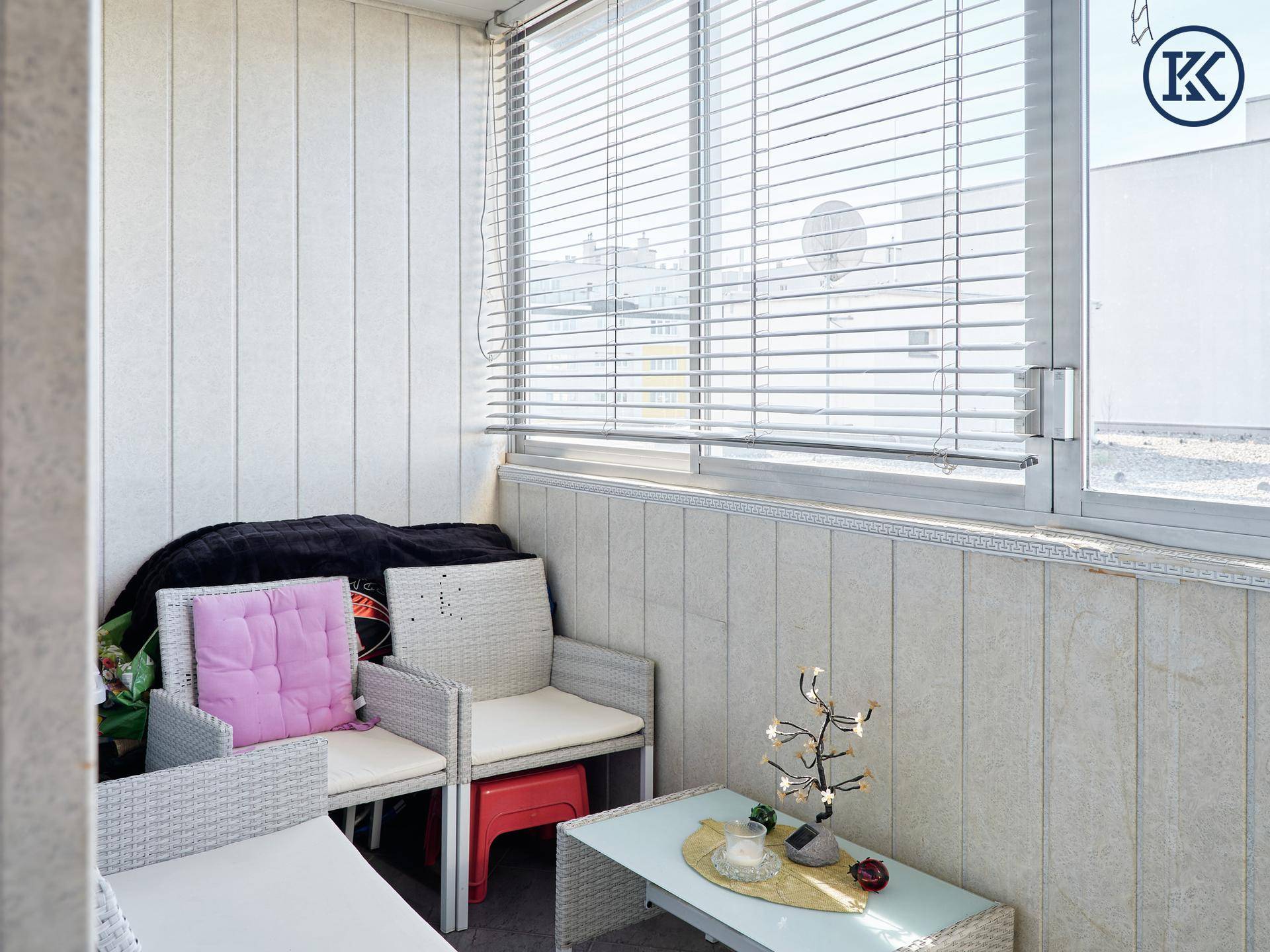 Gemütlicher, verglaster Balkon mit Sitzgelegenheiten und Jalousien.