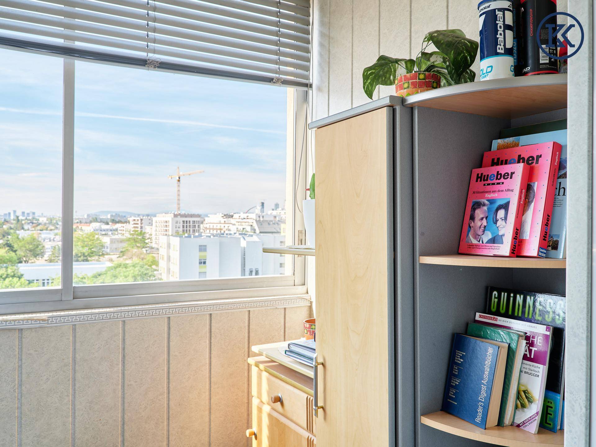 Heller Balkon mit Stadtblick und praktischem Regal für Bücher und Getränke.