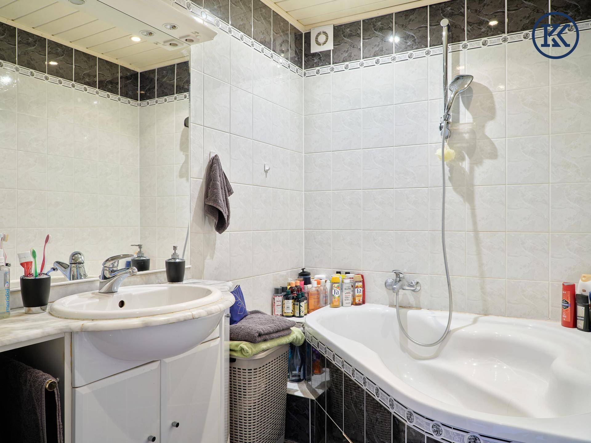 Badezimmer mit Badewanne, Waschbecken und Fliesen in Schwarz-Weiß.