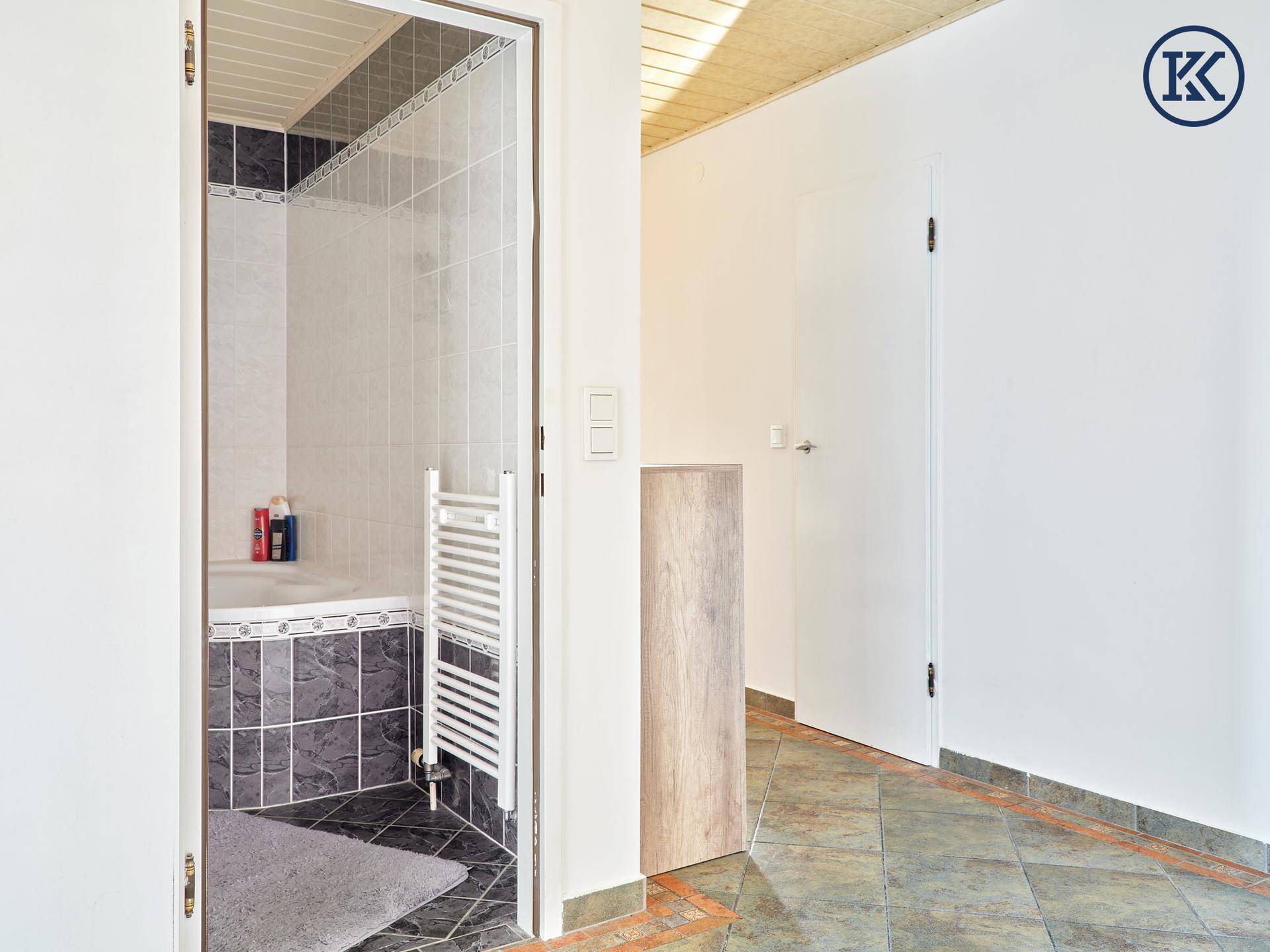 Flur mit Blick in das Badezimmer und Holzbalkendecke.