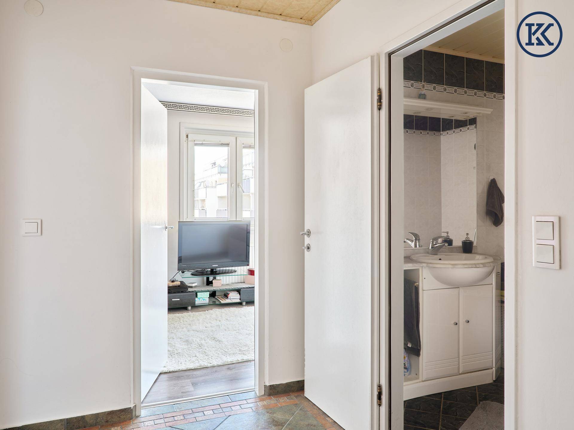 Flur mit Fliesenboden, der den Zugang zu einem Wohnzimmer und einem Badezimmer ermöglicht.