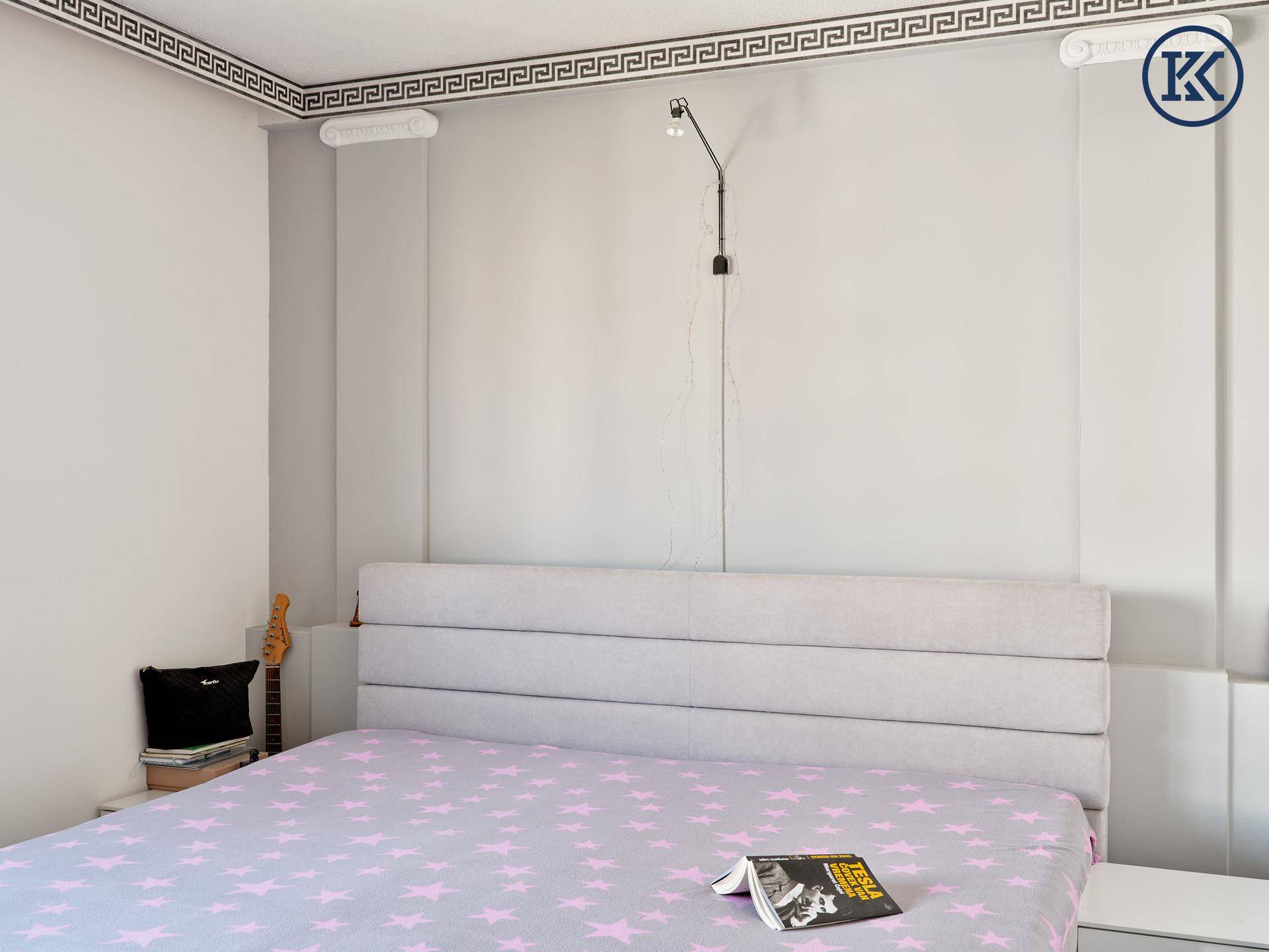 Schlafzimmer mit gepolstertem Kopfteil und Sternenmuster auf der Bettwäsche.