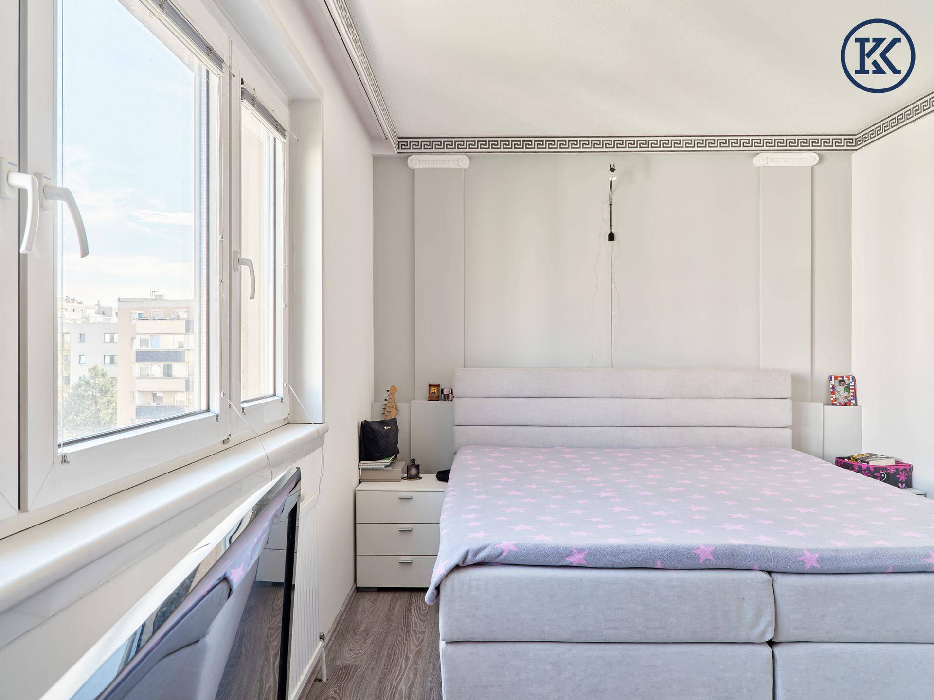Schlafzimmer mit großem Fenster, das den Raum erhellt, und einem bequemen Doppelbett mit Nachttisch.