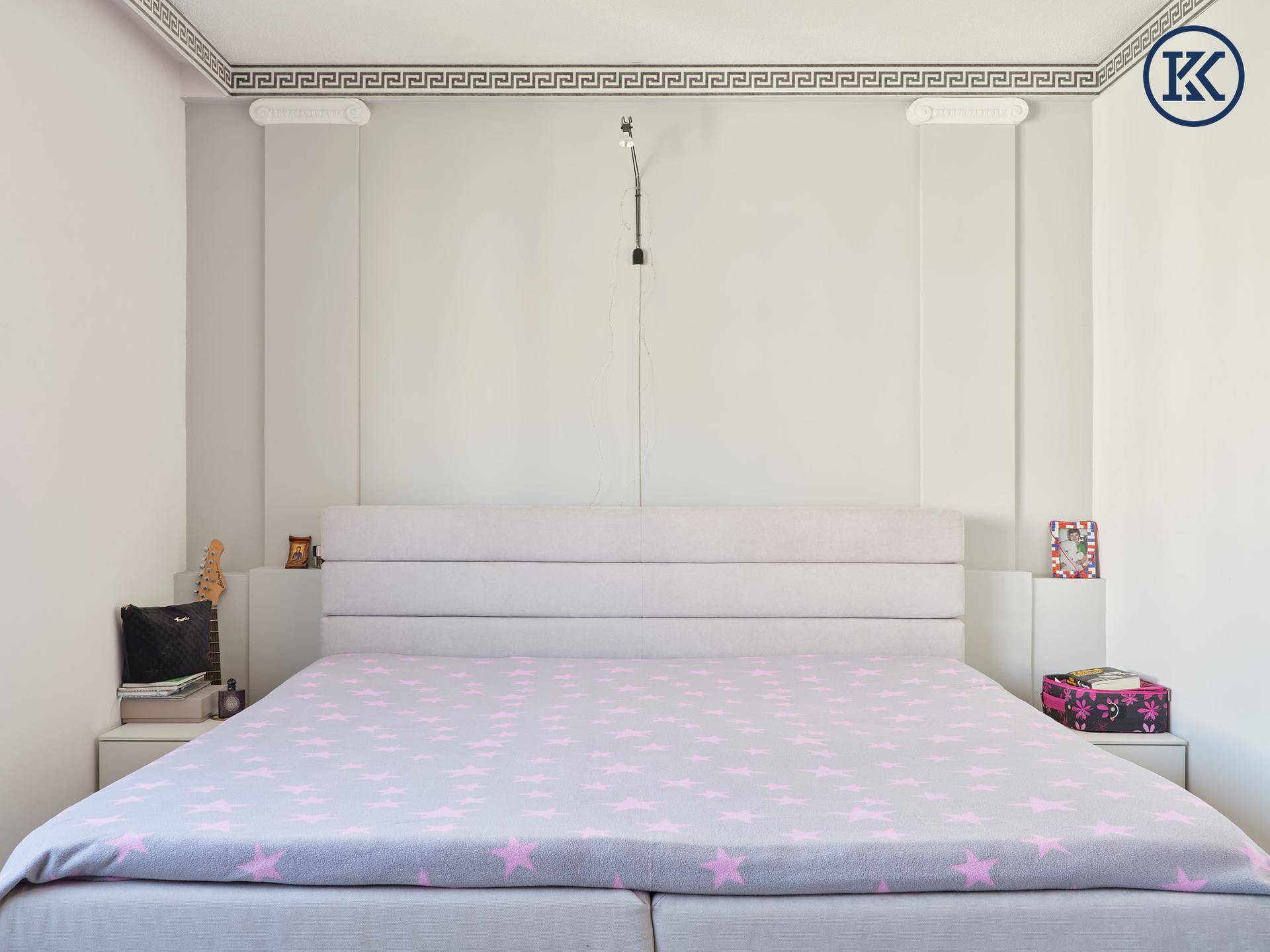 Großes Doppelbett mit gepolstertem Kopfteil und Nachttischen in einem modern eingerichteten Schlafzimmer.