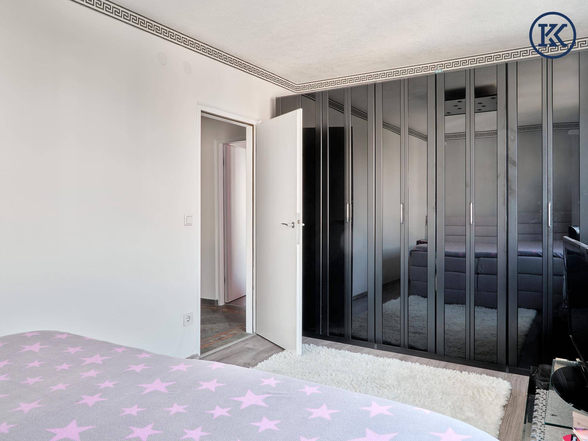 Schlafzimmer mit großen, verspiegelten Einbauschränken und Zugang zu einem angrenzenden Flur.