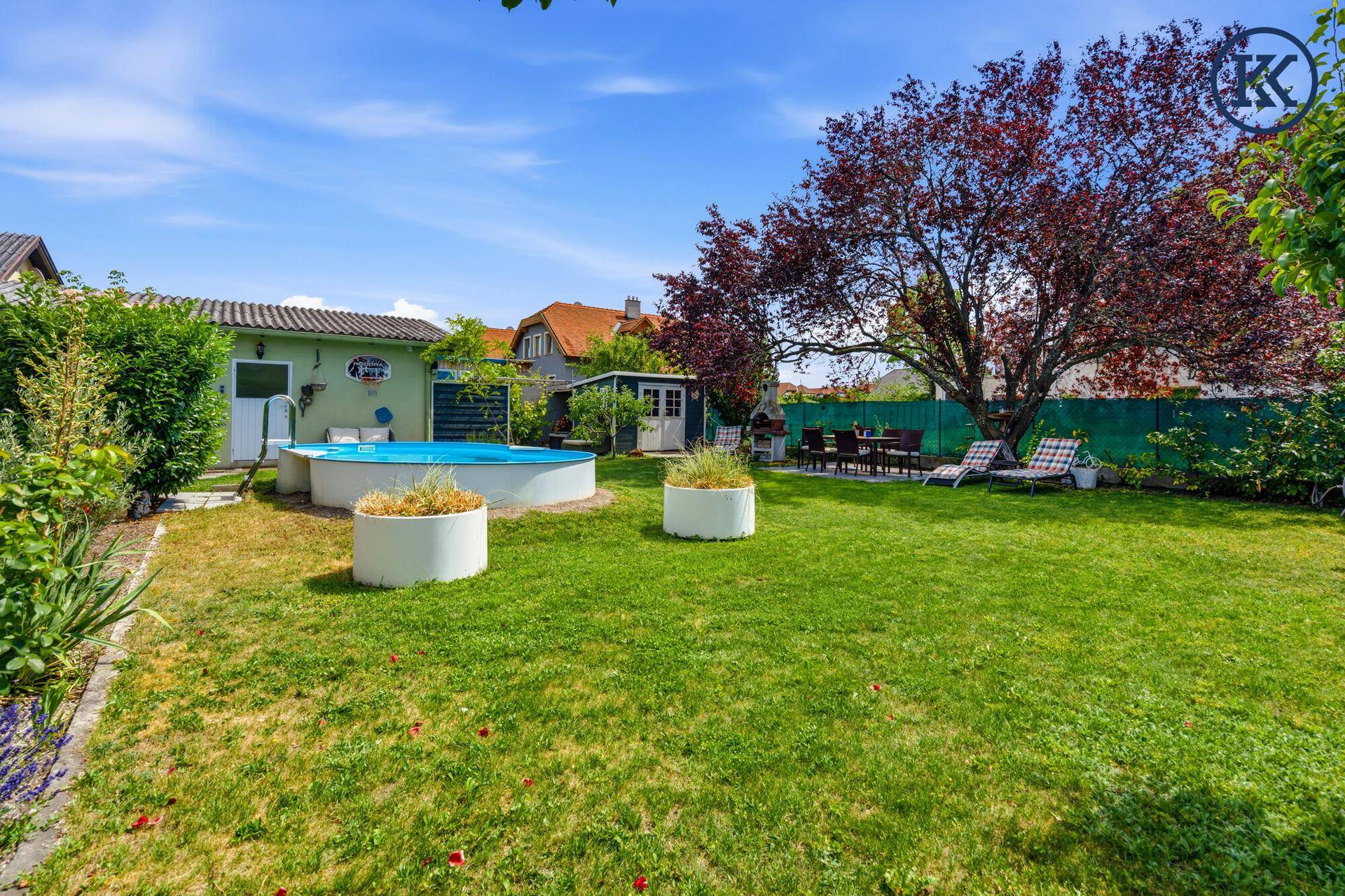 Gepflegter Garten mit Pool, Rasenfläche, Essbereich und Gartenhaus.