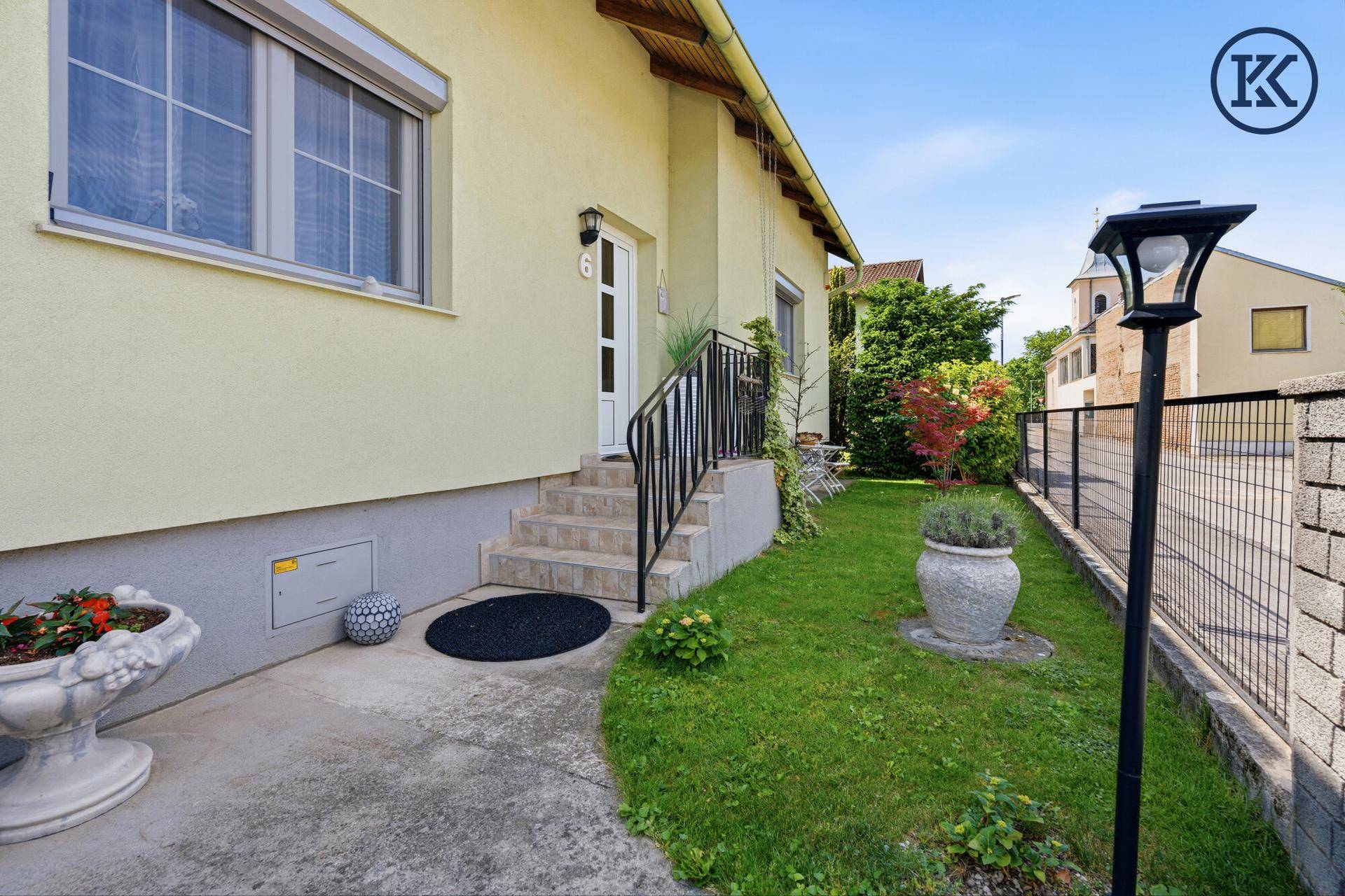 Vorderansicht des Hauses mit Eingang, Treppe und gepflegtem Vorgarten.