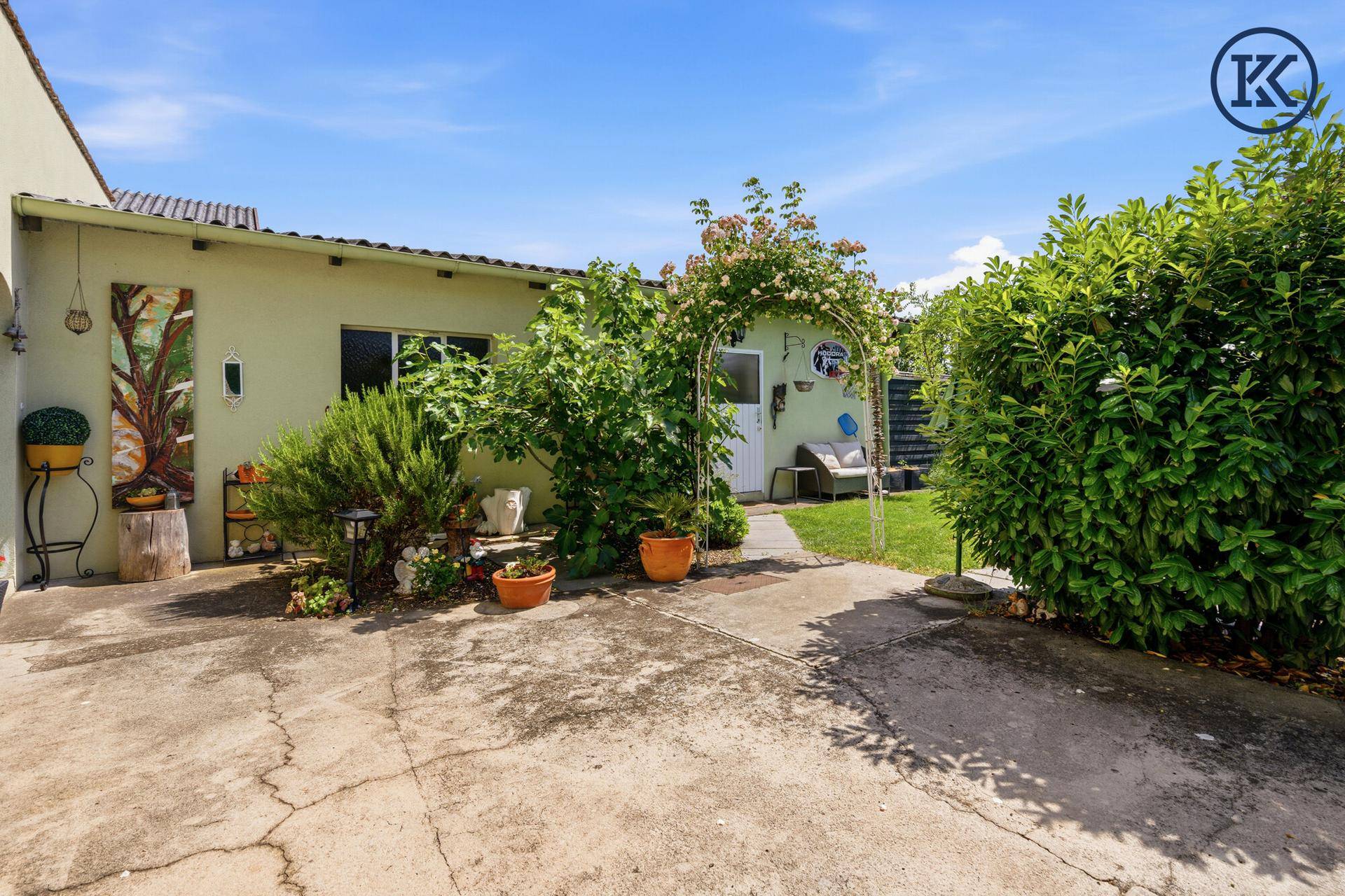 Eingangsbereich des Hauses mit gepflastertem Weg und grüner Bepflanzung.
