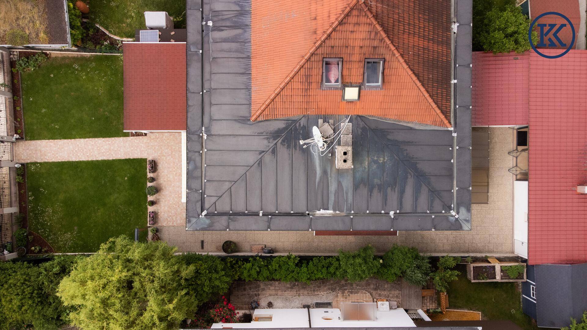 Vogelperspektive des Daches mit Ziegeln und Metallverkleidung sowie angrenzenden Grundstücken.