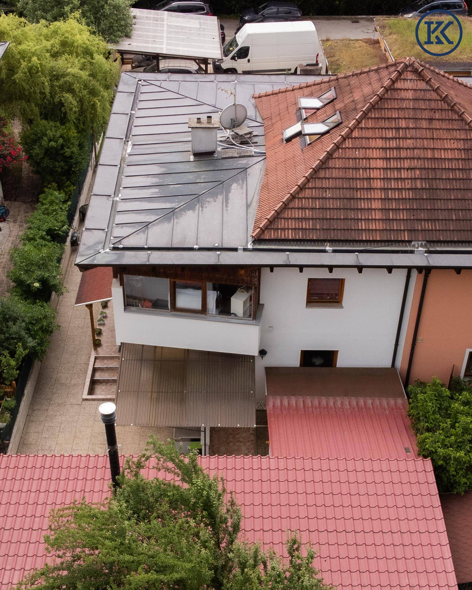 Nahaufnahme der Hausseite aus der Vogelperspektive mit Balkon und verschiedenen Dachstrukturen.
