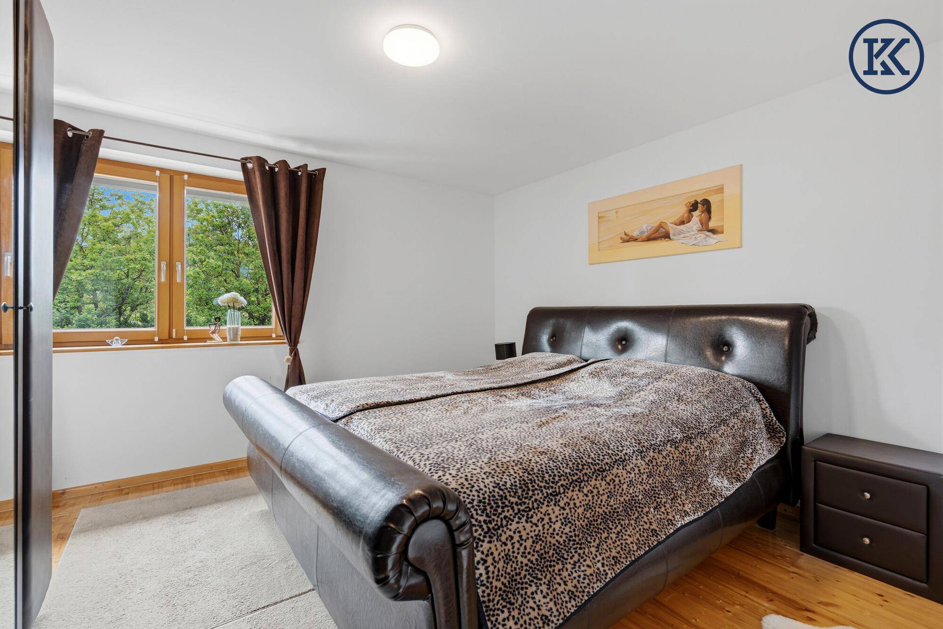Helles Schlafzimmer mit großem Bett, Holzboden und Fenster mit Blick ins Grüne.