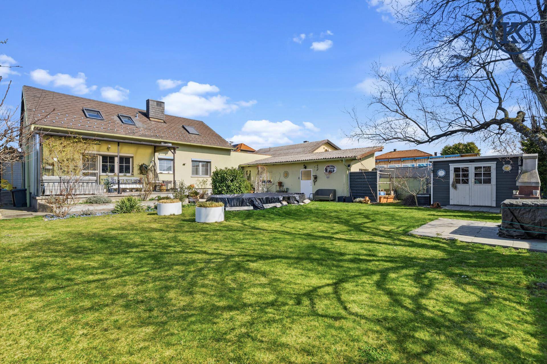 Weitläufiger Garten mit Rasenfläche, Gartenhaus und abgedecktem Poolbereich.
