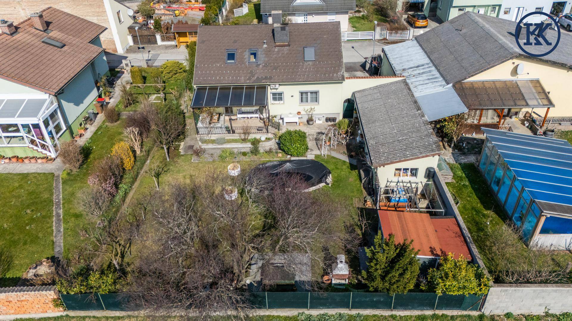 Luftaufnahme des Hauses mit großem Garten, Pool und umliegenden Wohnhäusern.