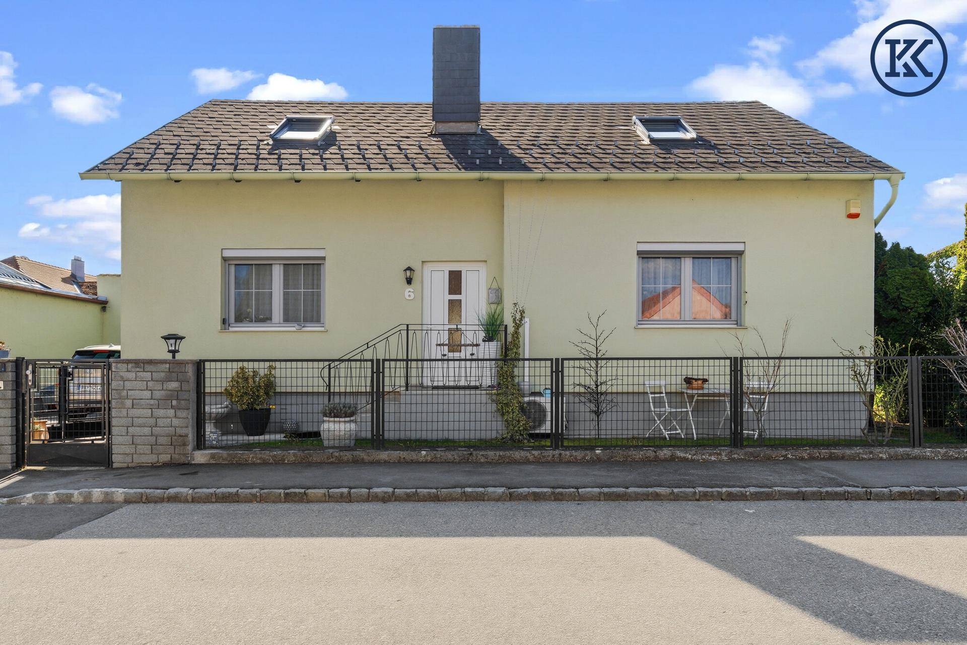 Vorderansicht des Einfamilienhauses mit Vorgarten, Zaun und Eingangsbereich.