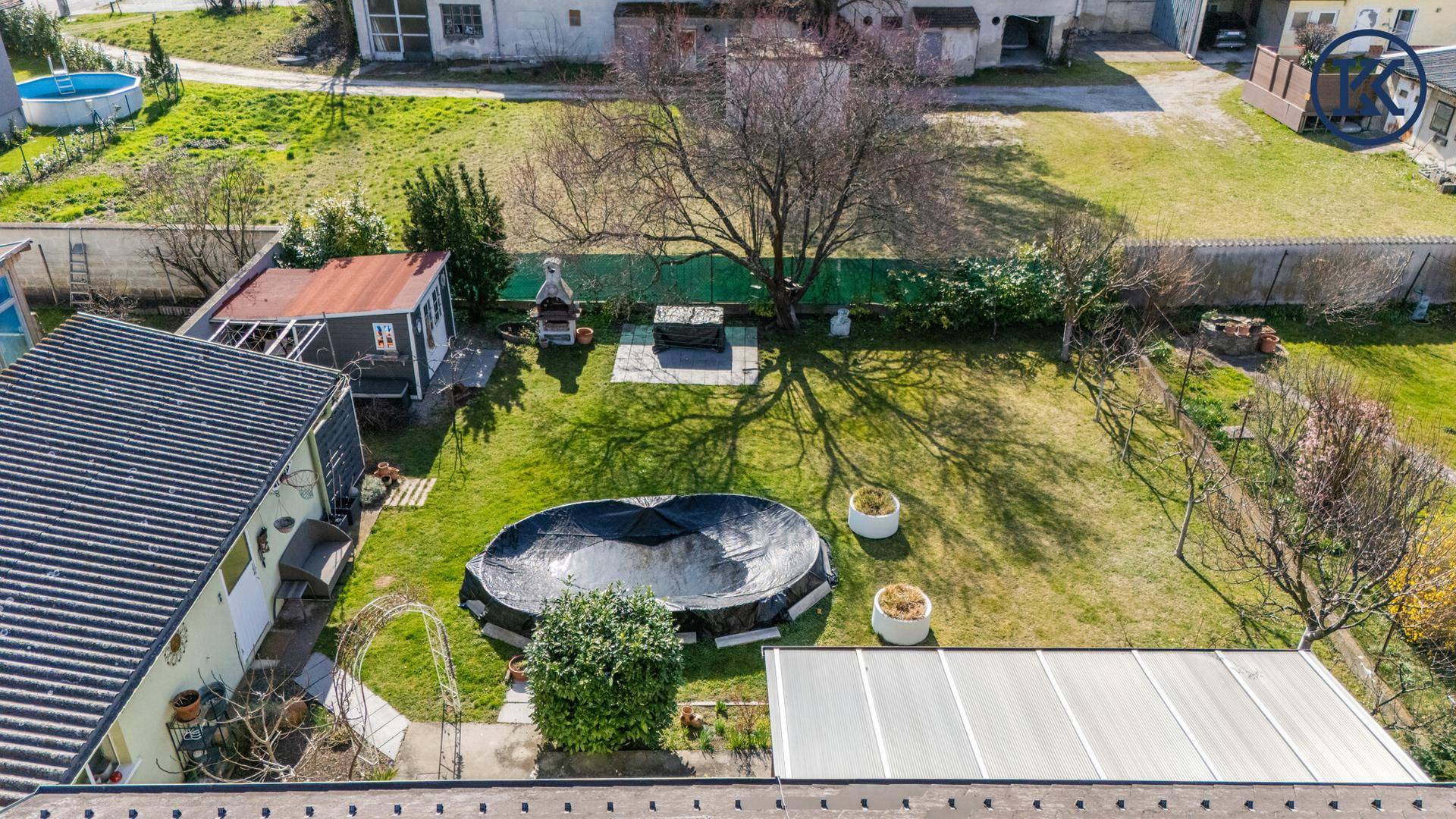 Luftaufnahme des weitläufigen Gartens mit Rasenfläche und abgedecktem Pool.