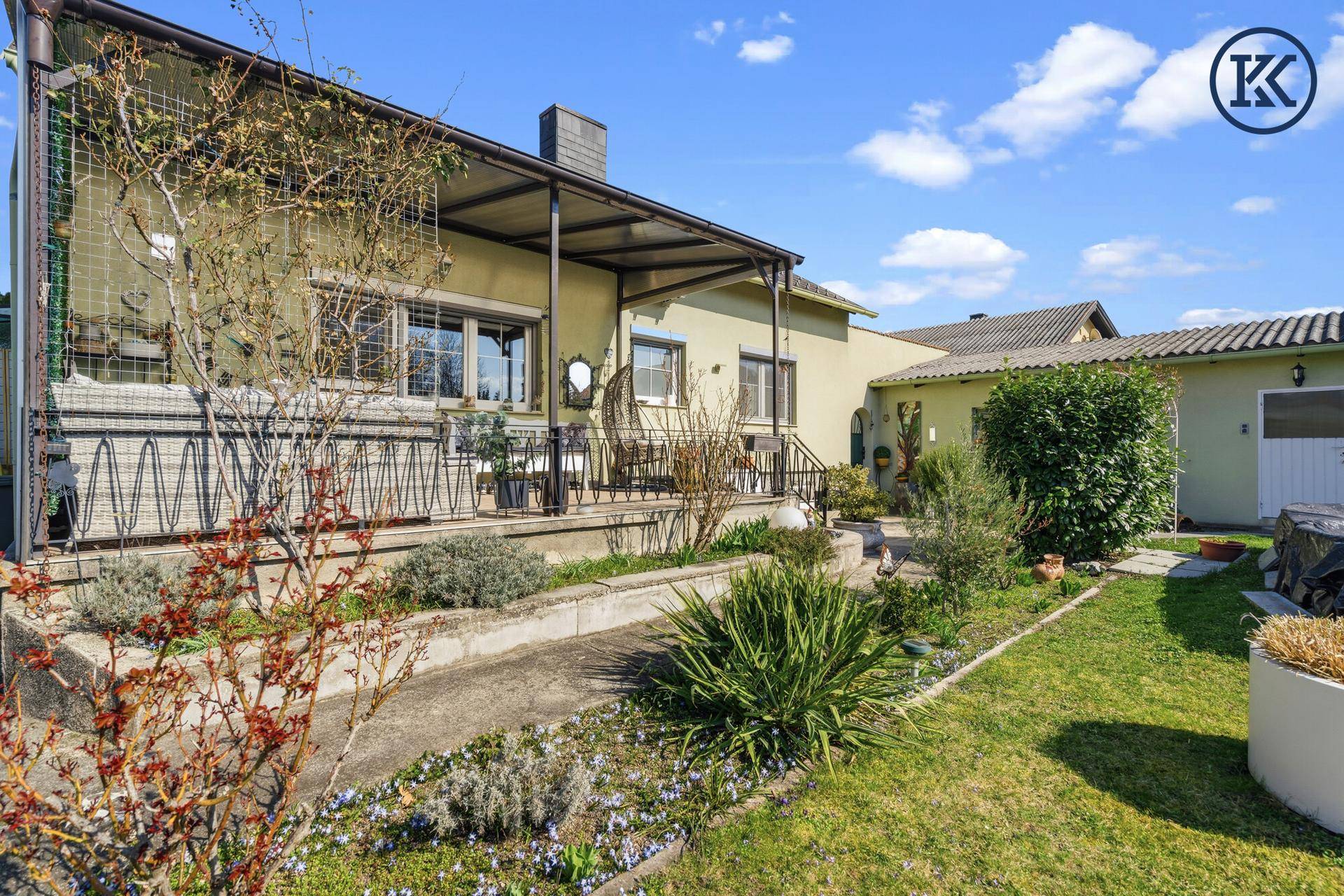 Überdachte Terrasse mit Sitzgelegenheiten und Blick auf den gepflegten Gartenbereich.