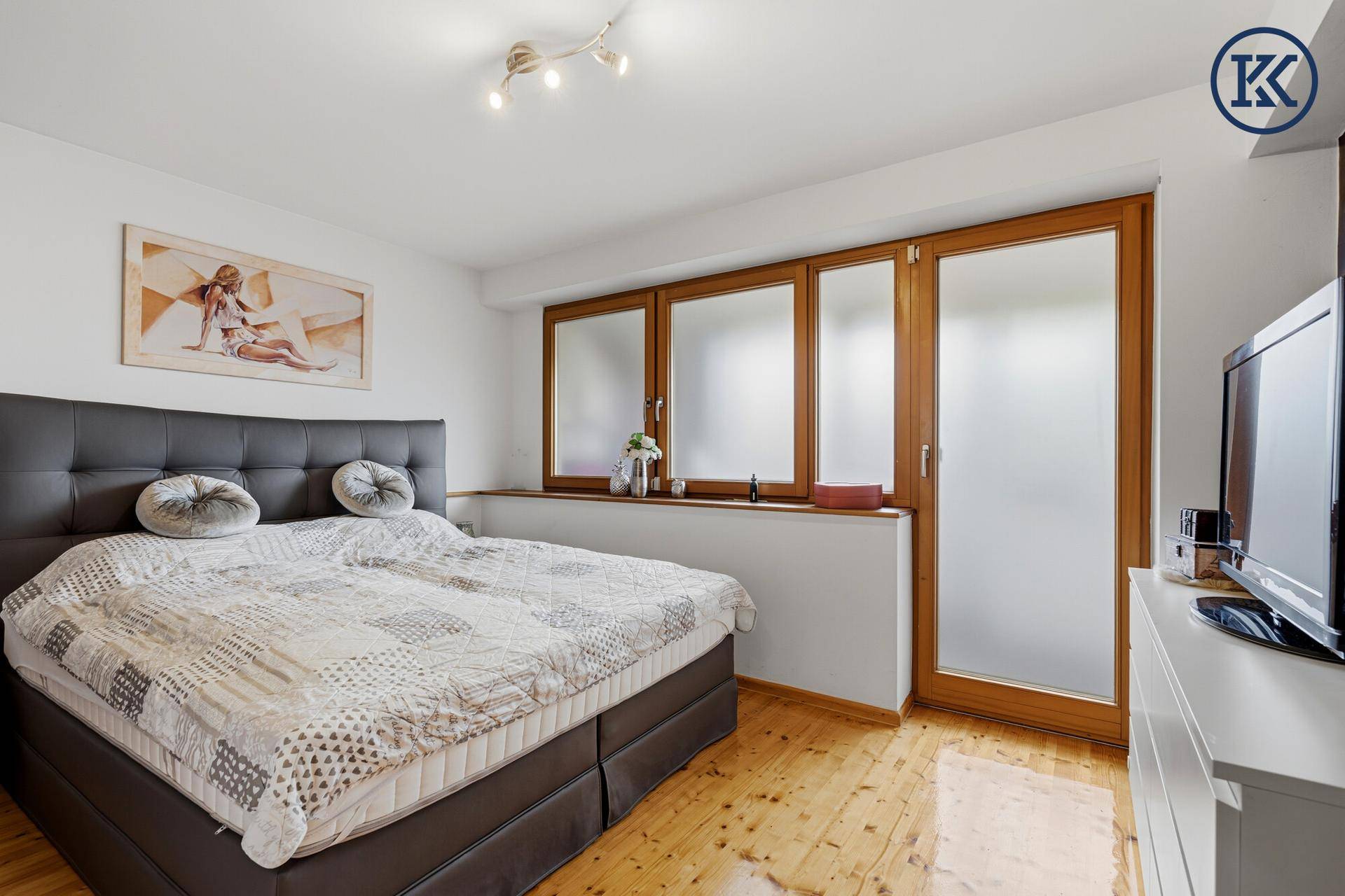 Geräumiges Schlafzimmer mit Doppelbett, Holzboden und großen Fenstern.