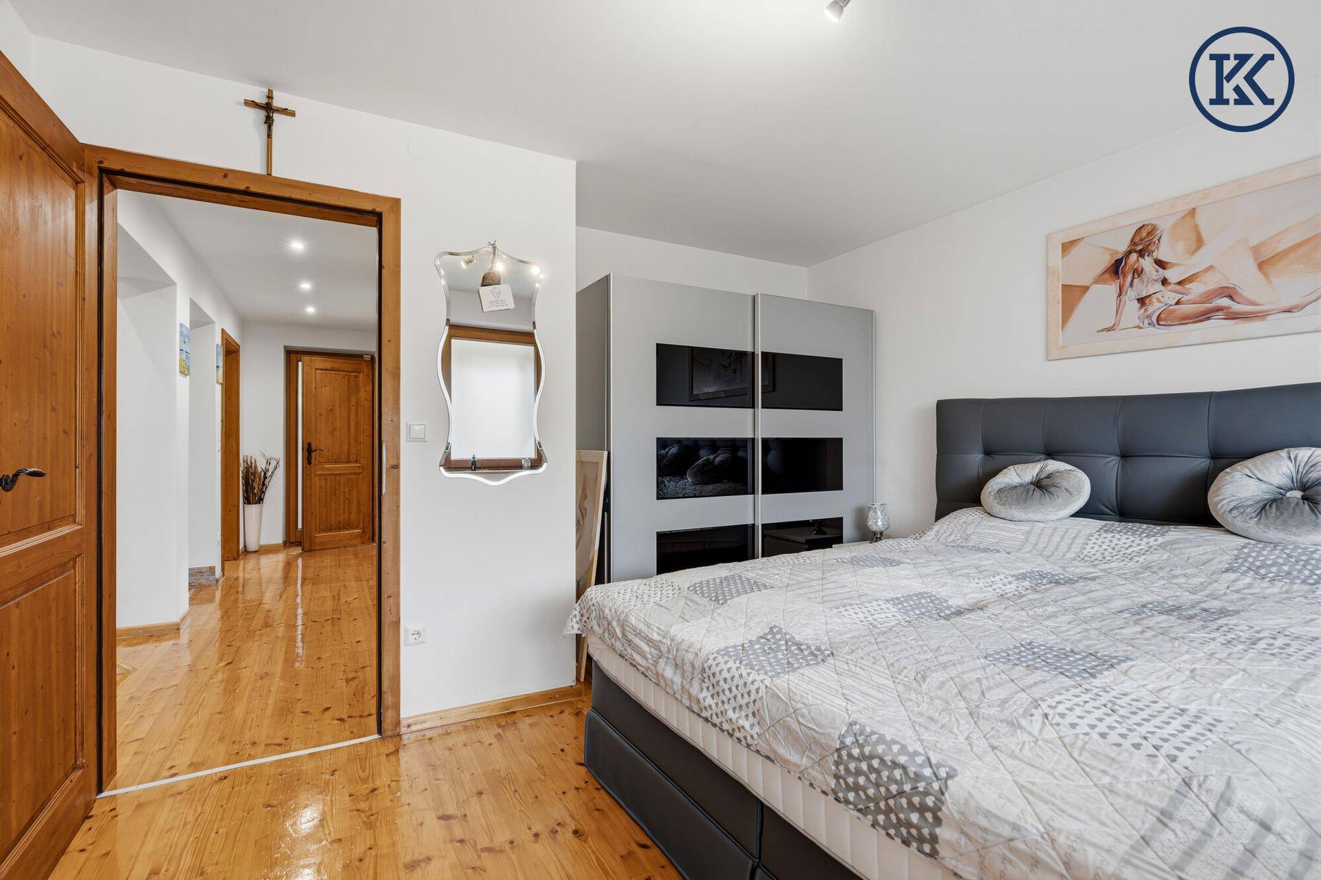 Schlafzimmer mit Holzboden, Doppelbett und Zugang zum Flur.
