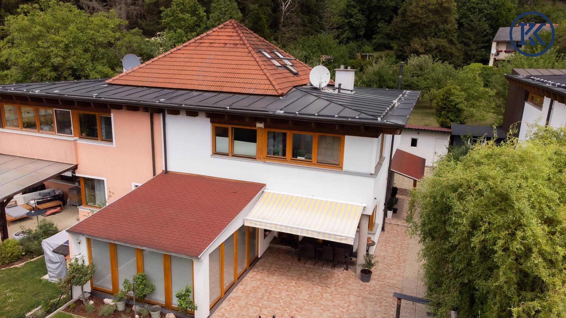 Vogelperspektive des Hauses mit rotem Ziegeldach, Terrasse und Gartenbereich.